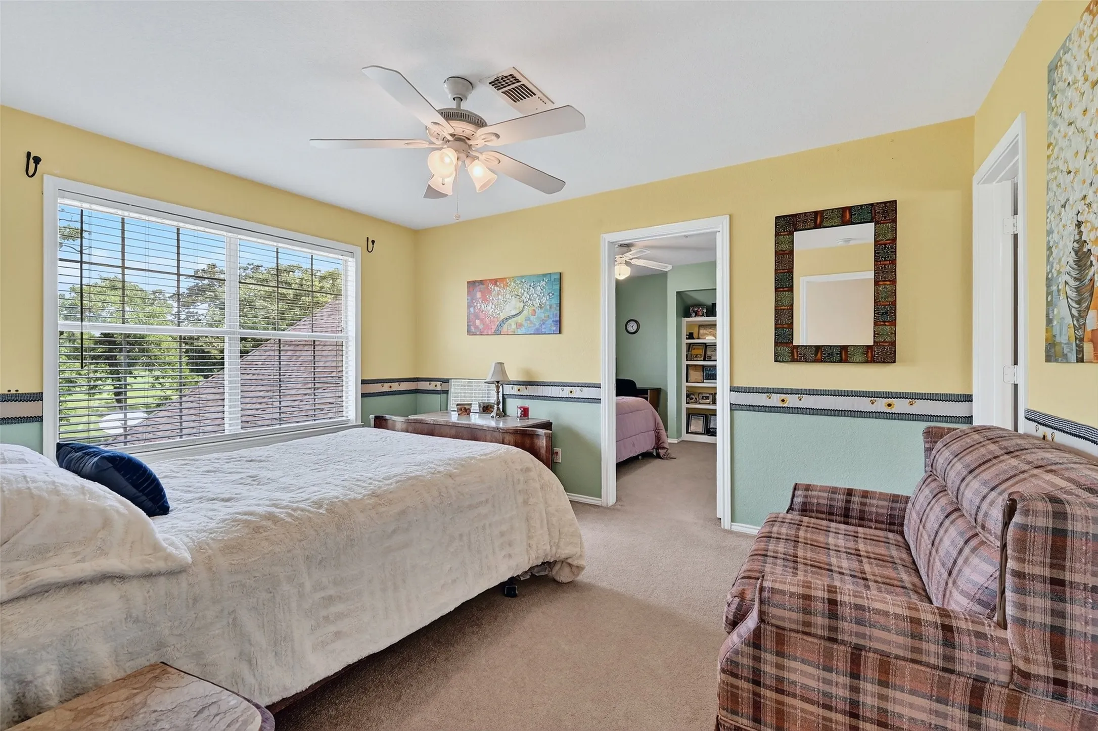 Carpeted bedroom featuring a walk in closet and ceiling fan