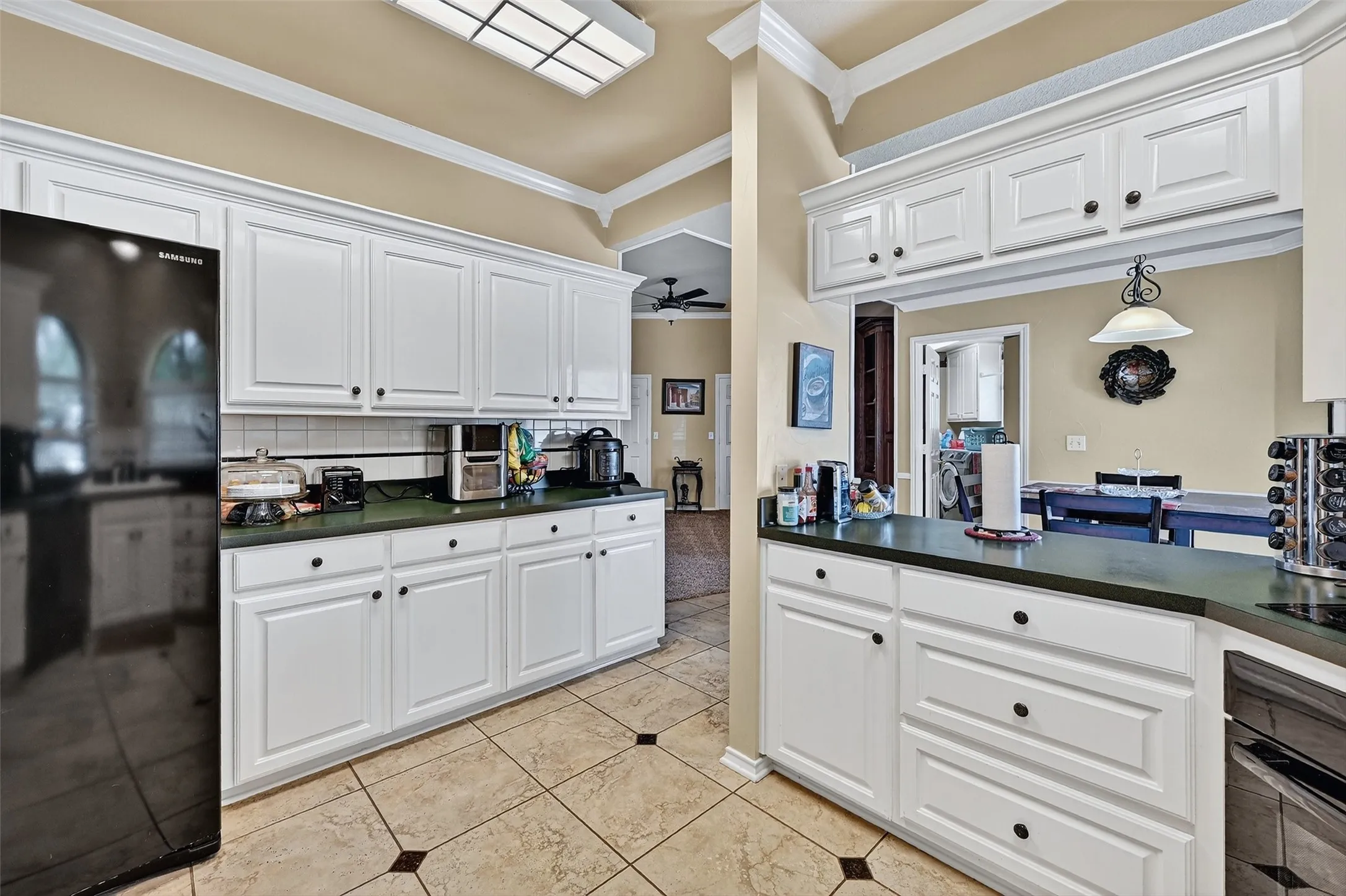 Kitchen with black appliances, crown molding, dark countertops, and ceiling fan