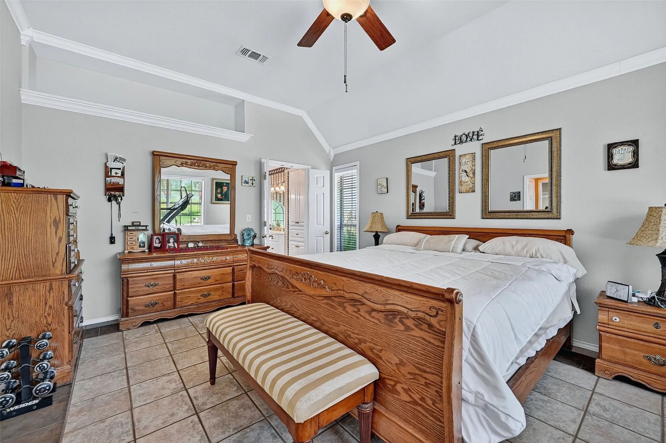 Bedroom with lofted ceiling, light tile patterned floors, ornamental molding, and ceiling fan