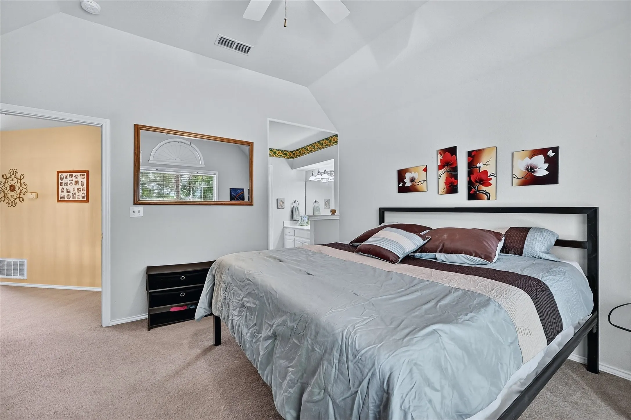 Bedroom with carpet floors, vaulted ceiling, ensuite bathroom, and a ceiling fan