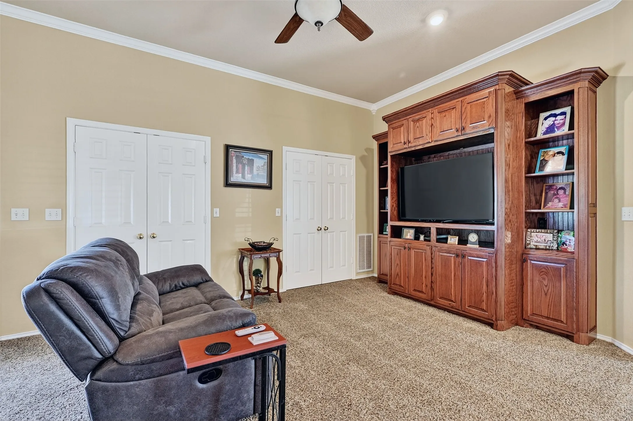 Living area with light carpet, a ceiling fan, and ornamental molding