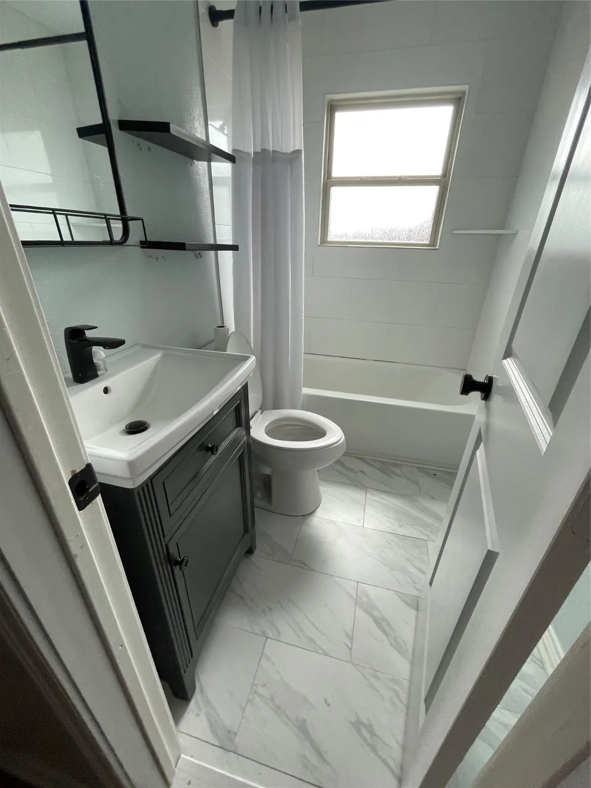 Bathroom with vanity, marble look tile flooring, and shower / tub combo with curtain