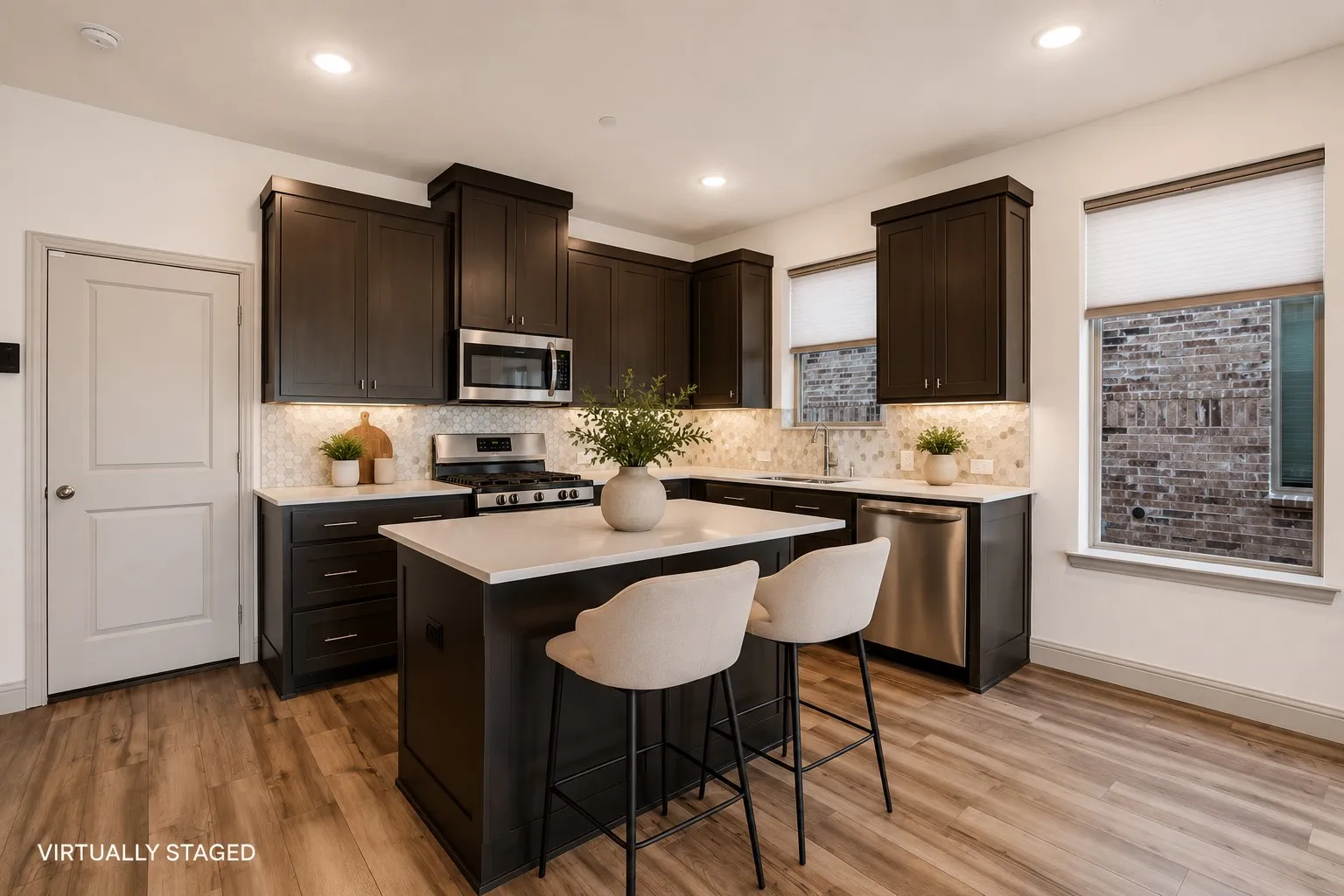 Modern kitchen featuring dark wood cabinetry, stainless steel appliances, a white stone countertop island with seating, patterned tile backsplash, and wood-finish flooring