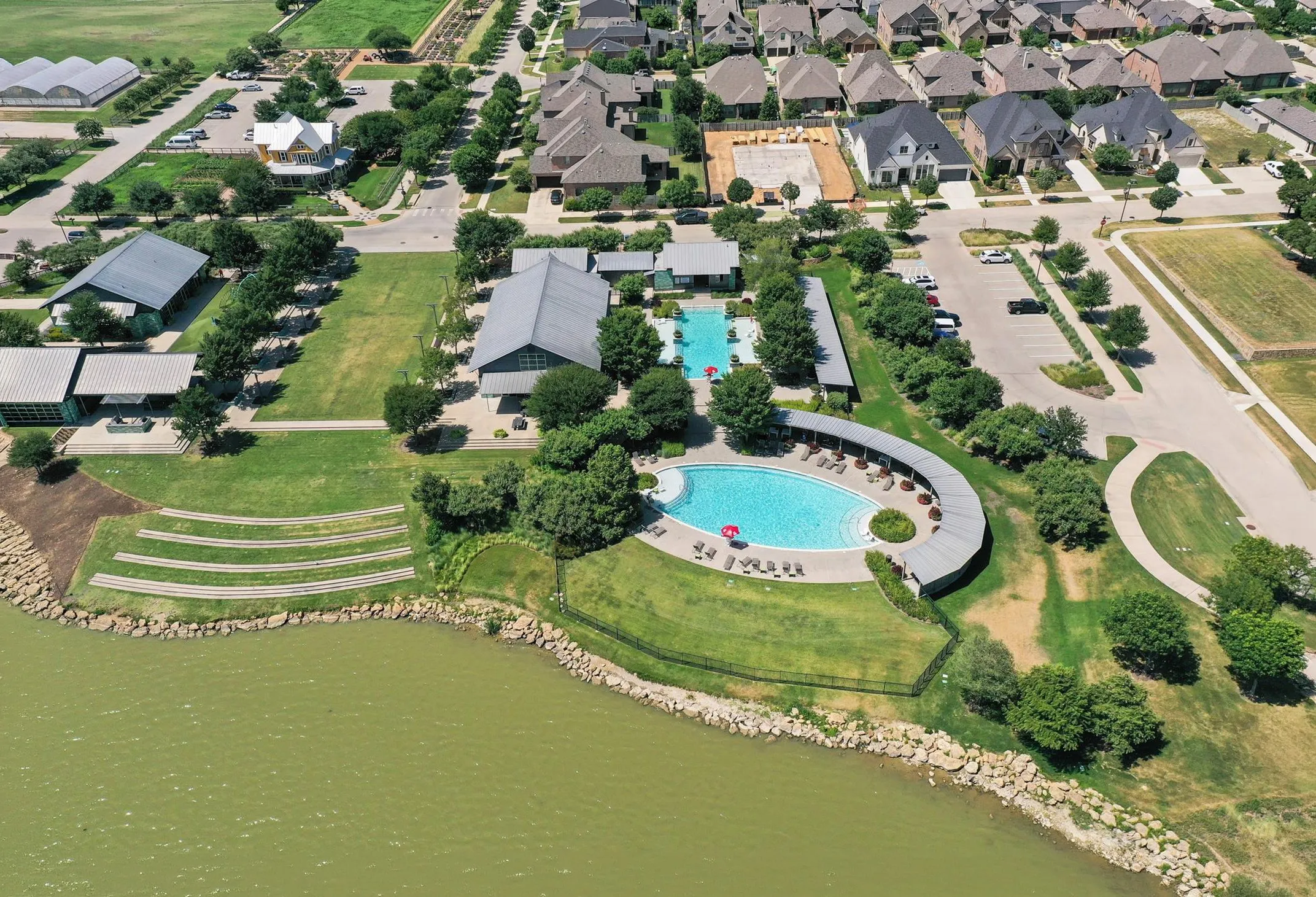 Aerial view showcasing a community with multiple swimming pools, extensive green spaces, and contemporary residential architecture