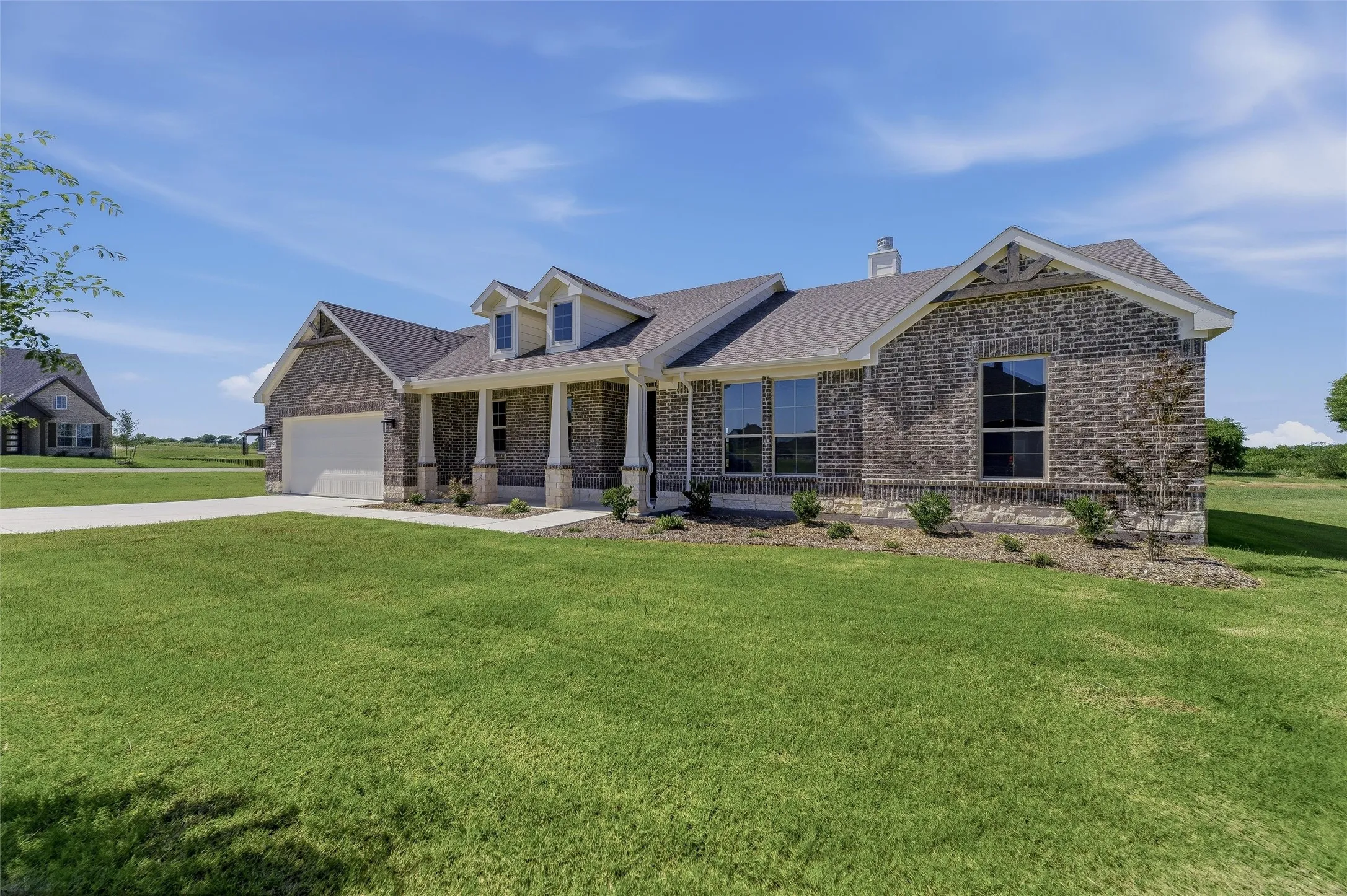 Brick and stone facade residence featuring a covered front porch with columns