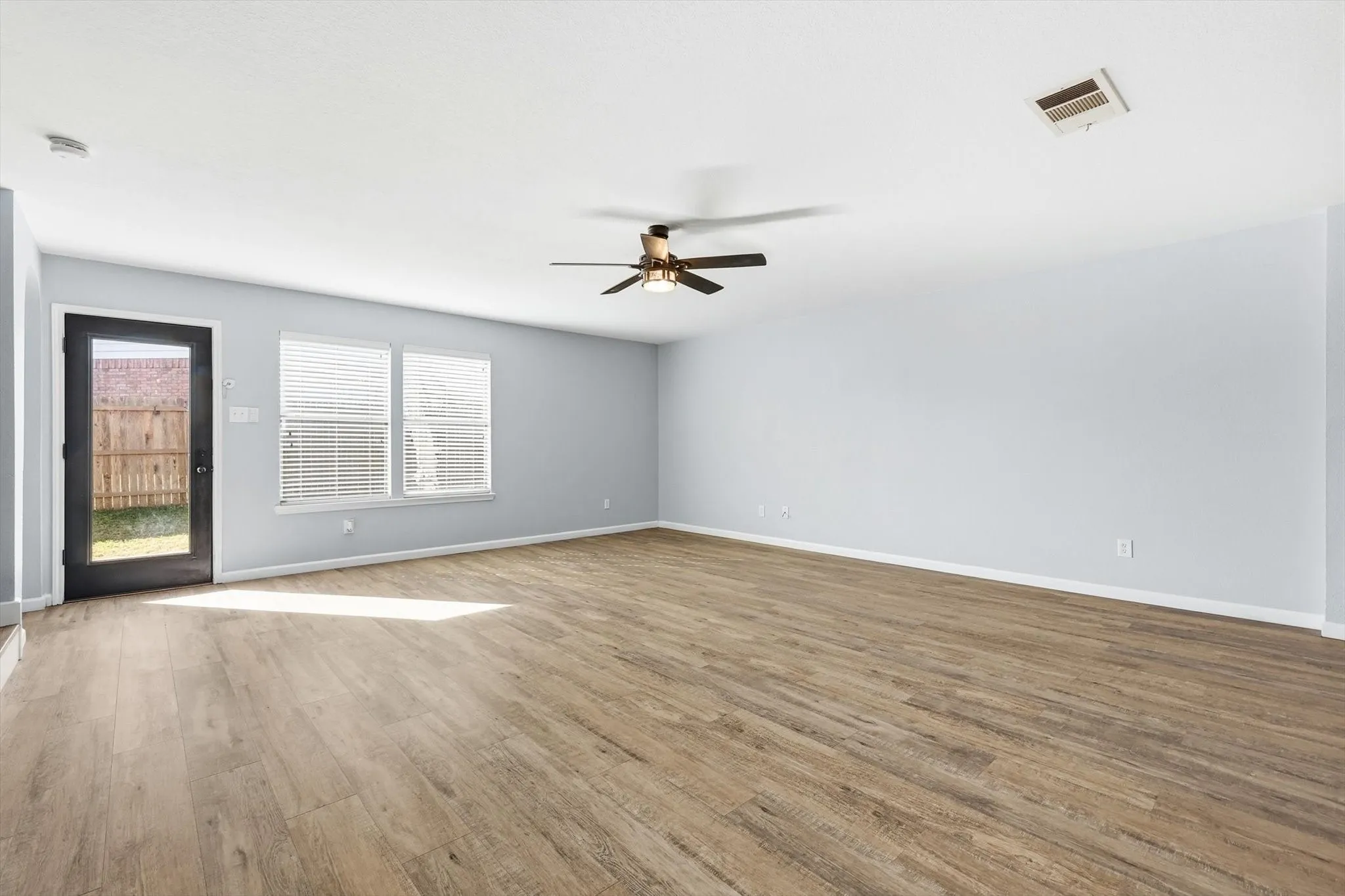 Unfurnished living room with arched walkways, ceiling fan, light wood-type flooring, and stairs