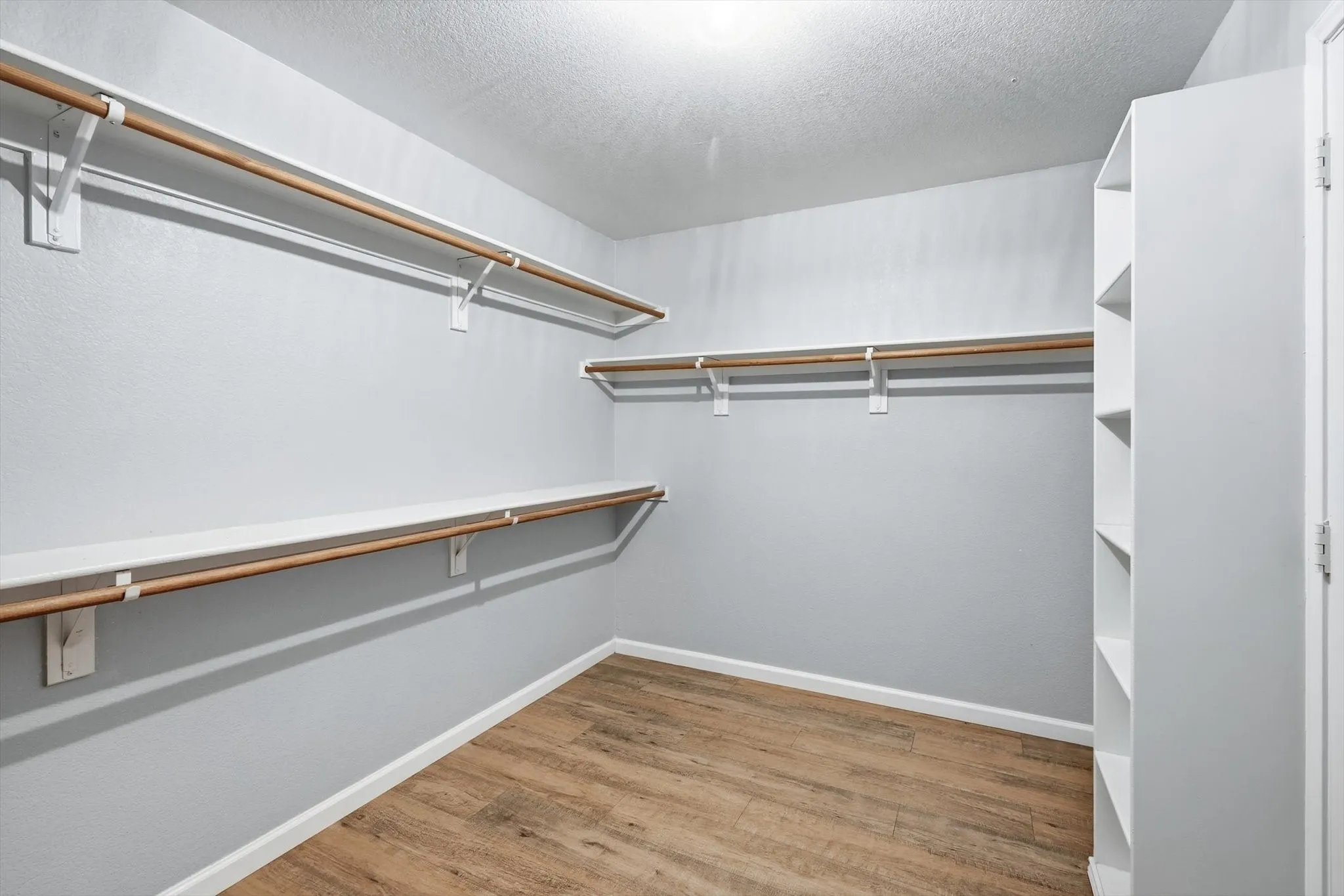 Unfurnished room with attic access, light wood-style floors, a ceiling fan, and arched walkways