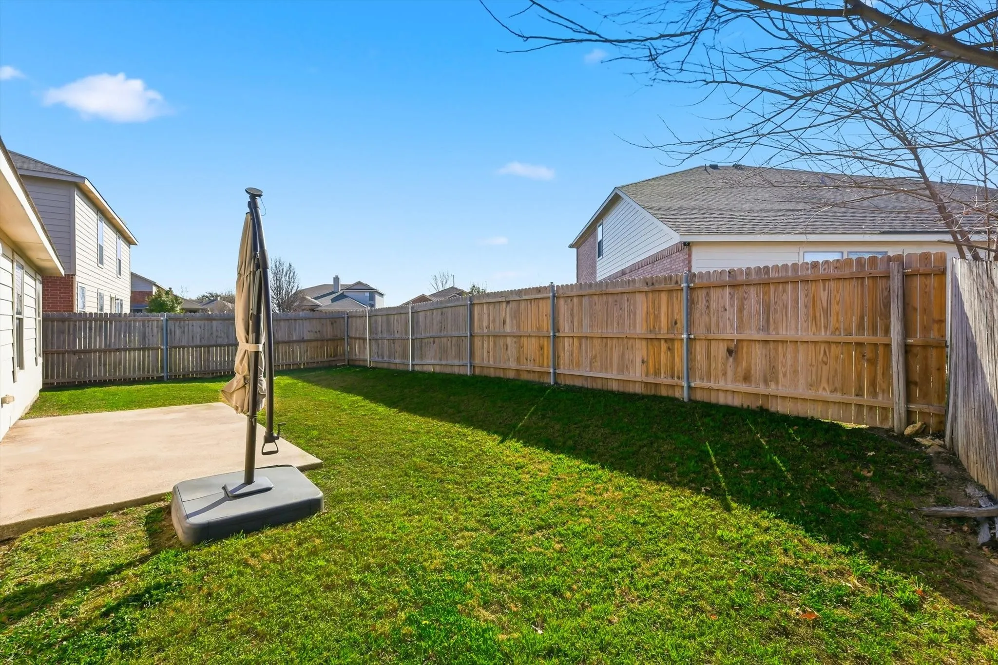 Rear view of property with a patio area, roof with shingles, a fenced backyard, and brick siding
