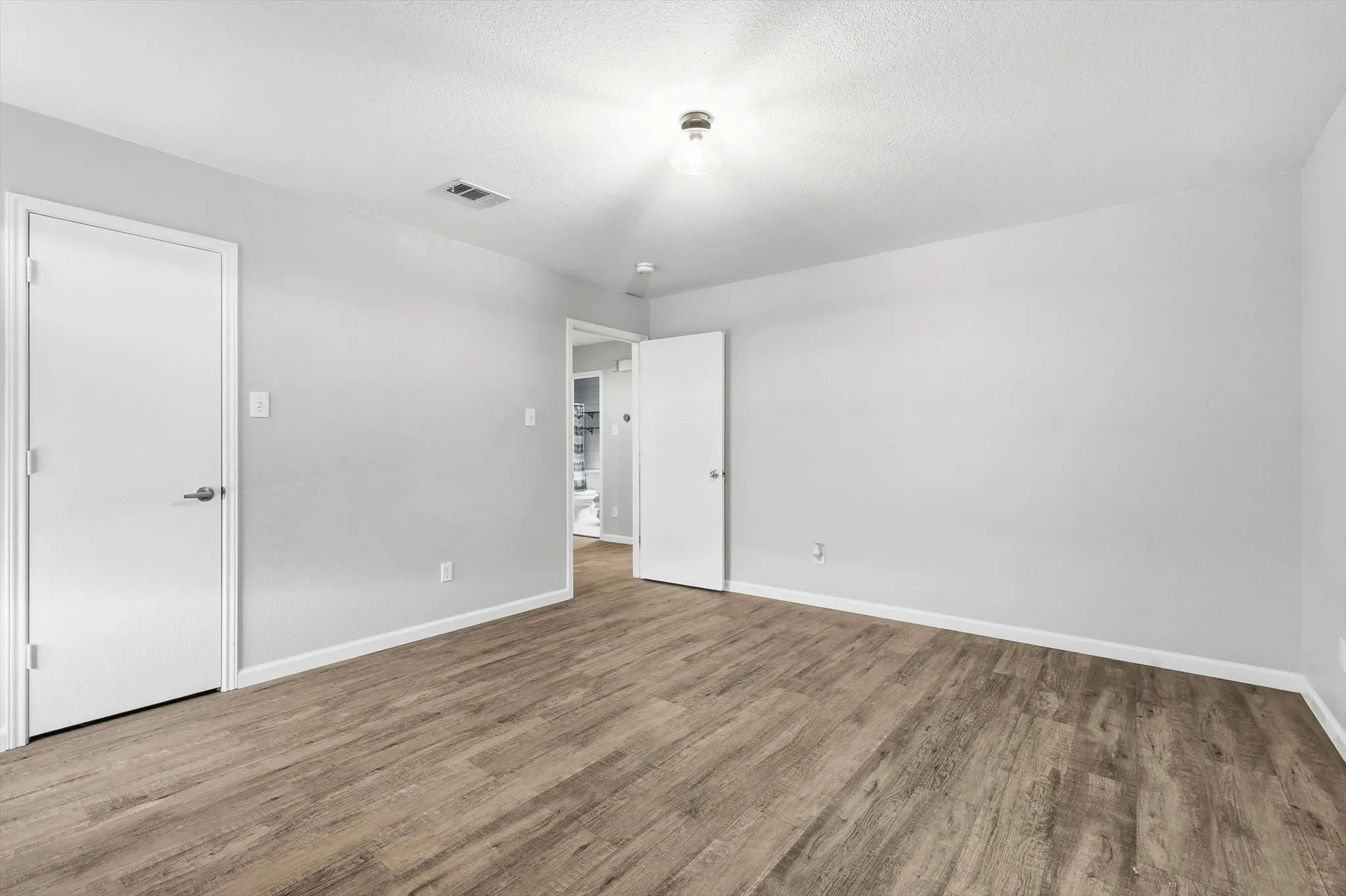 Unfurnished bedroom featuring wood finished floors and a textured ceiling