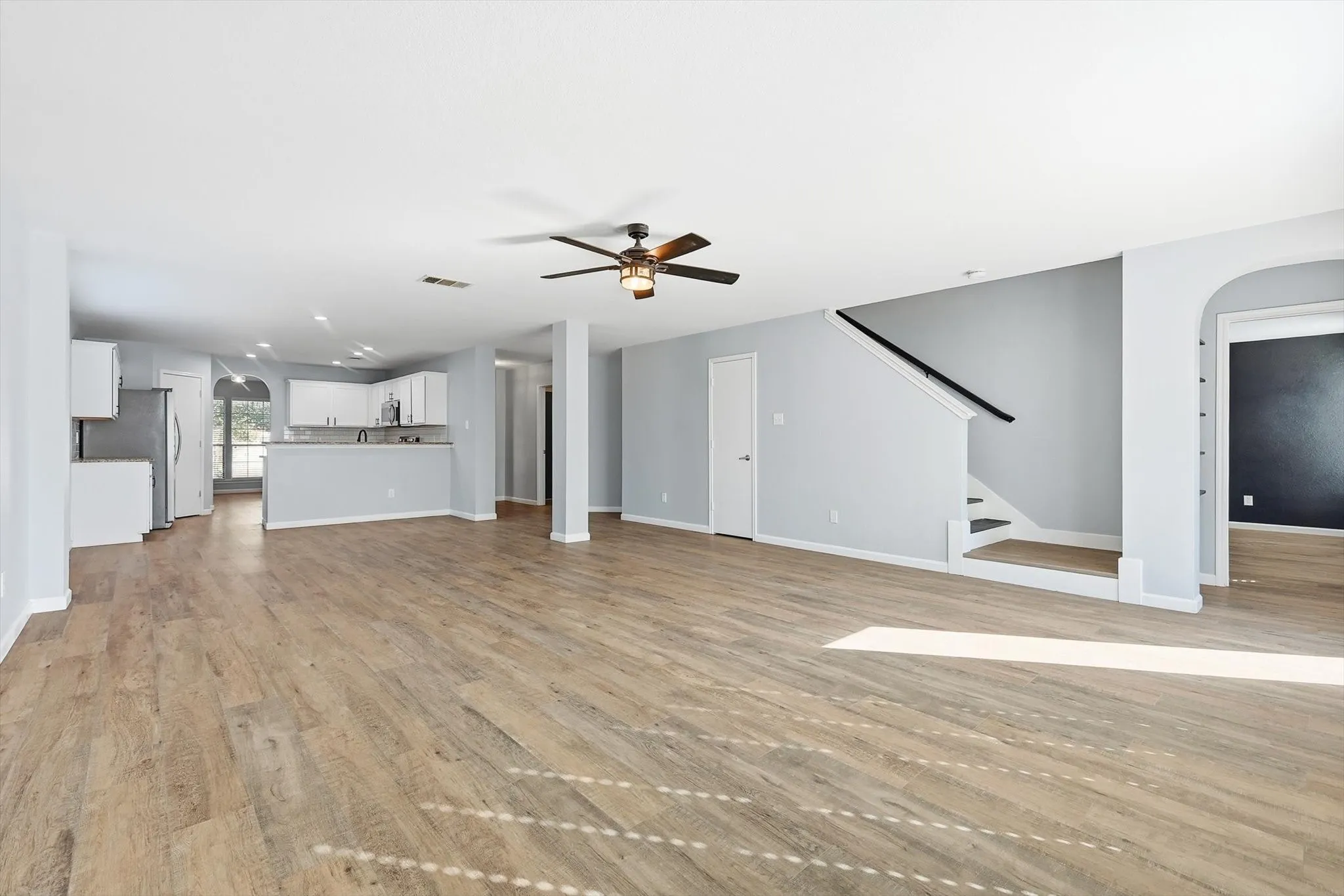 Unfurnished living room featuring light wood-style flooring, a ceiling fan, and recessed lighting