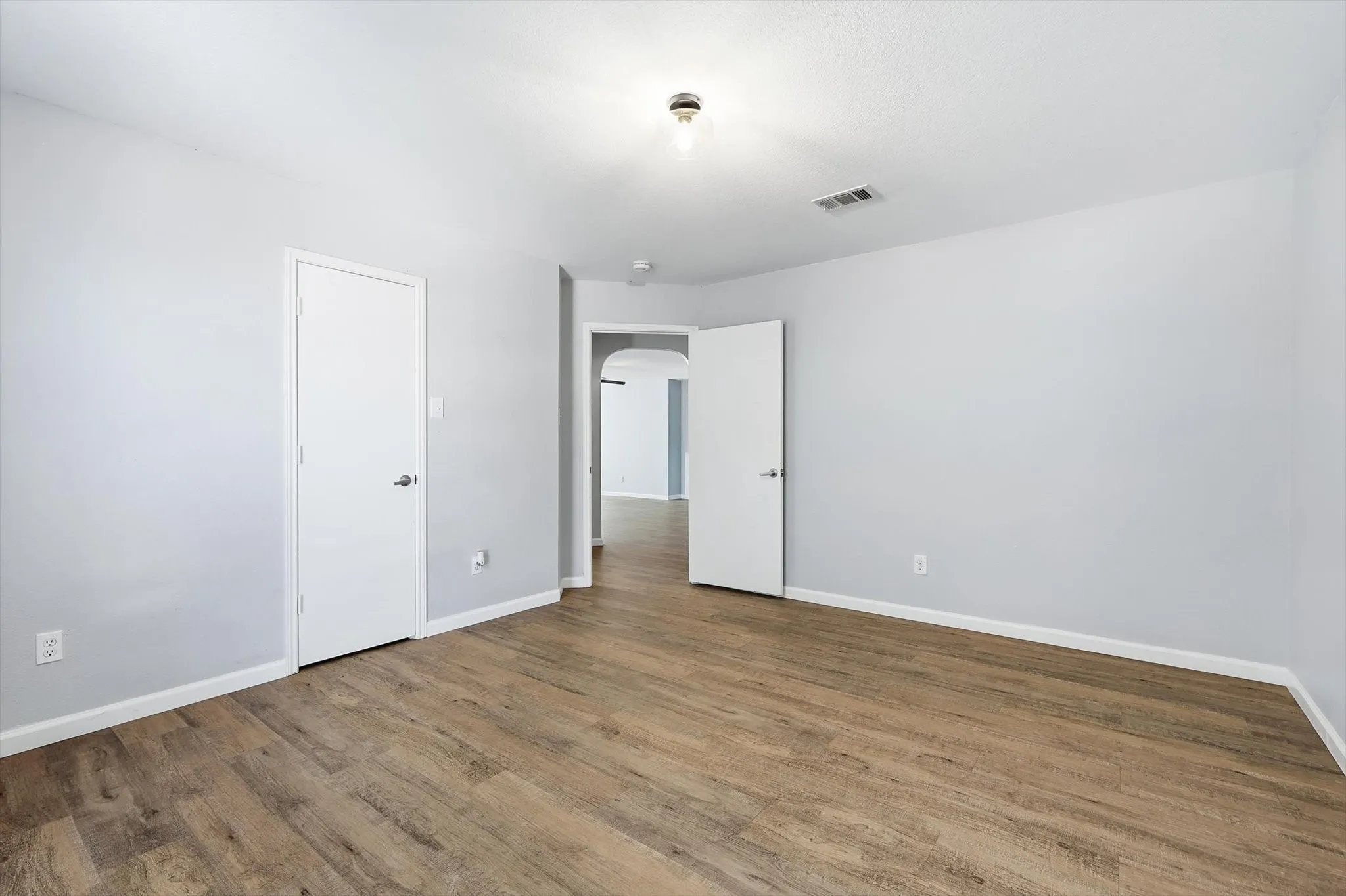 Empty room with light wood finished floors and a textured ceiling