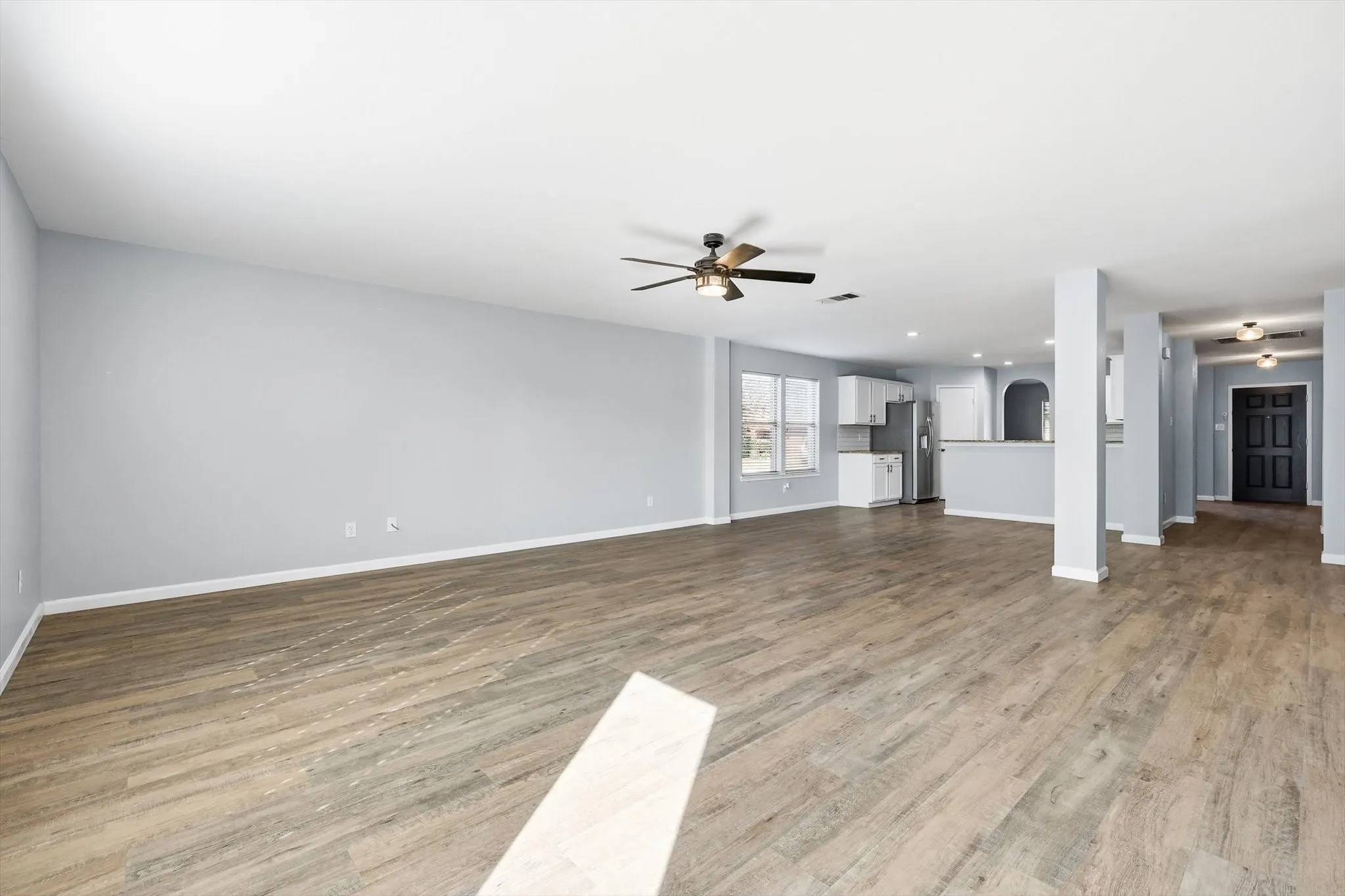 Unfurnished living room featuring light wood-style flooring, a ceiling fan, and recessed lighting