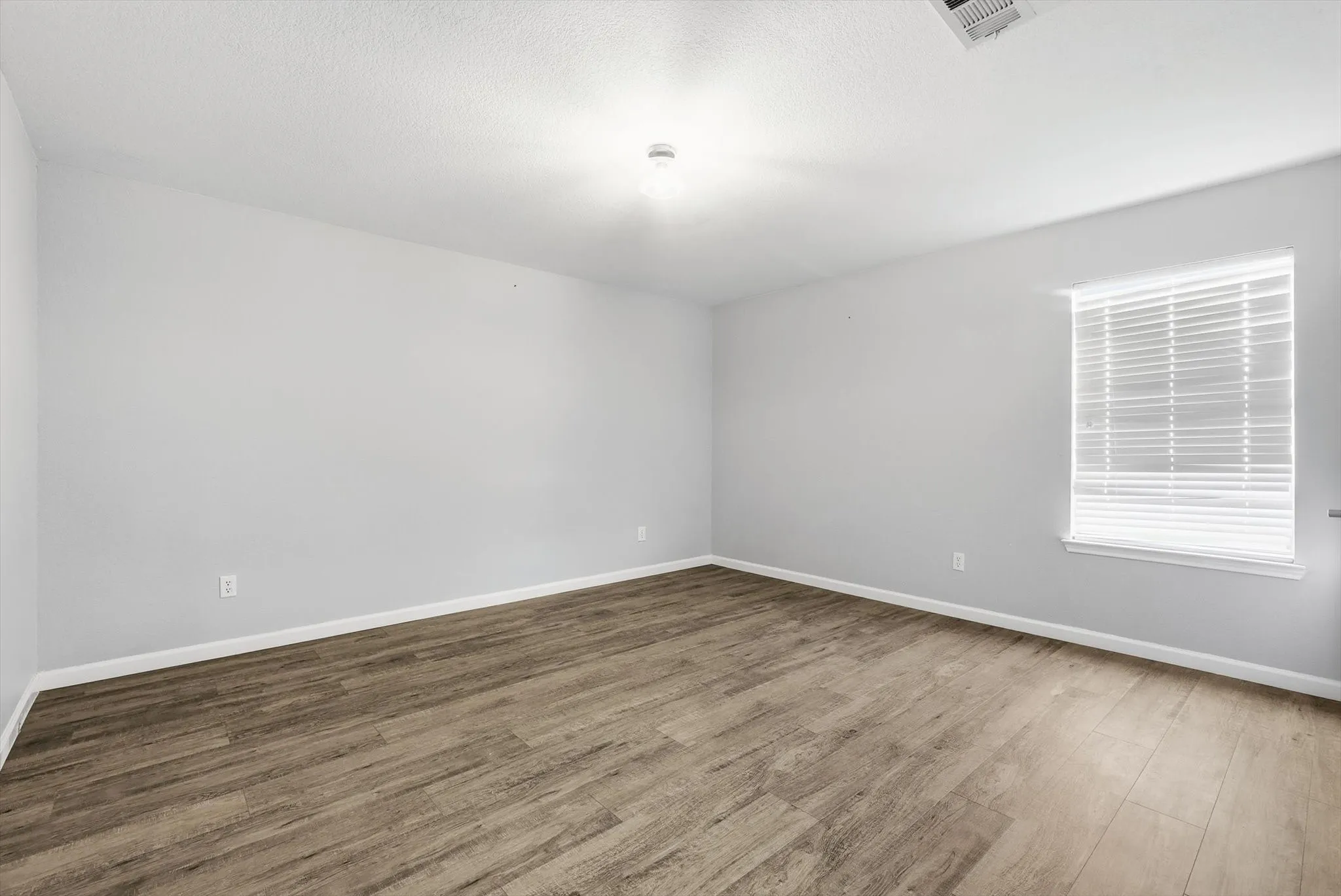 Unfurnished bedroom featuring wood finished floors and a textured ceiling