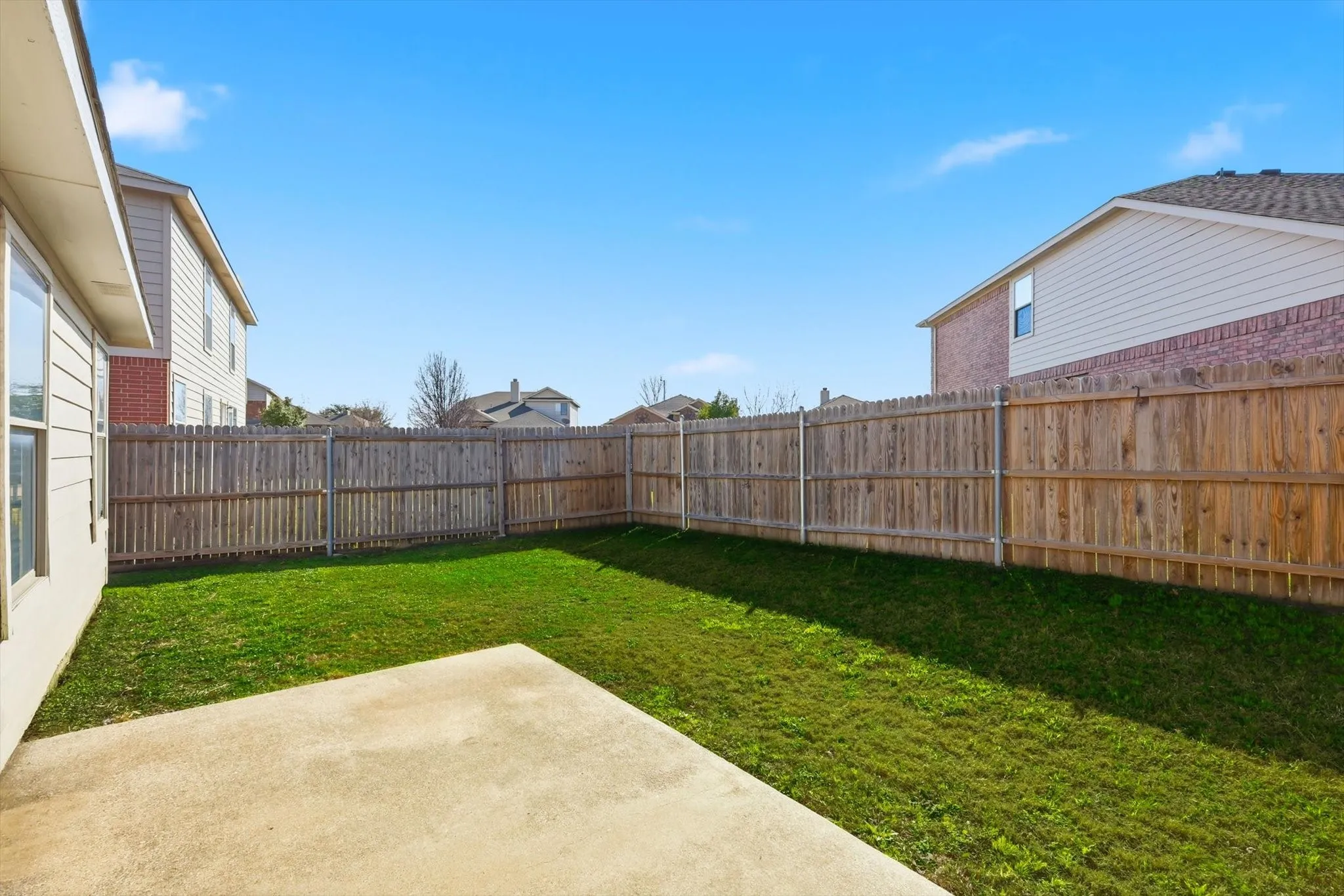 Rear view of property featuring a patio, a fenced backyard, a shingled roof, and brick siding