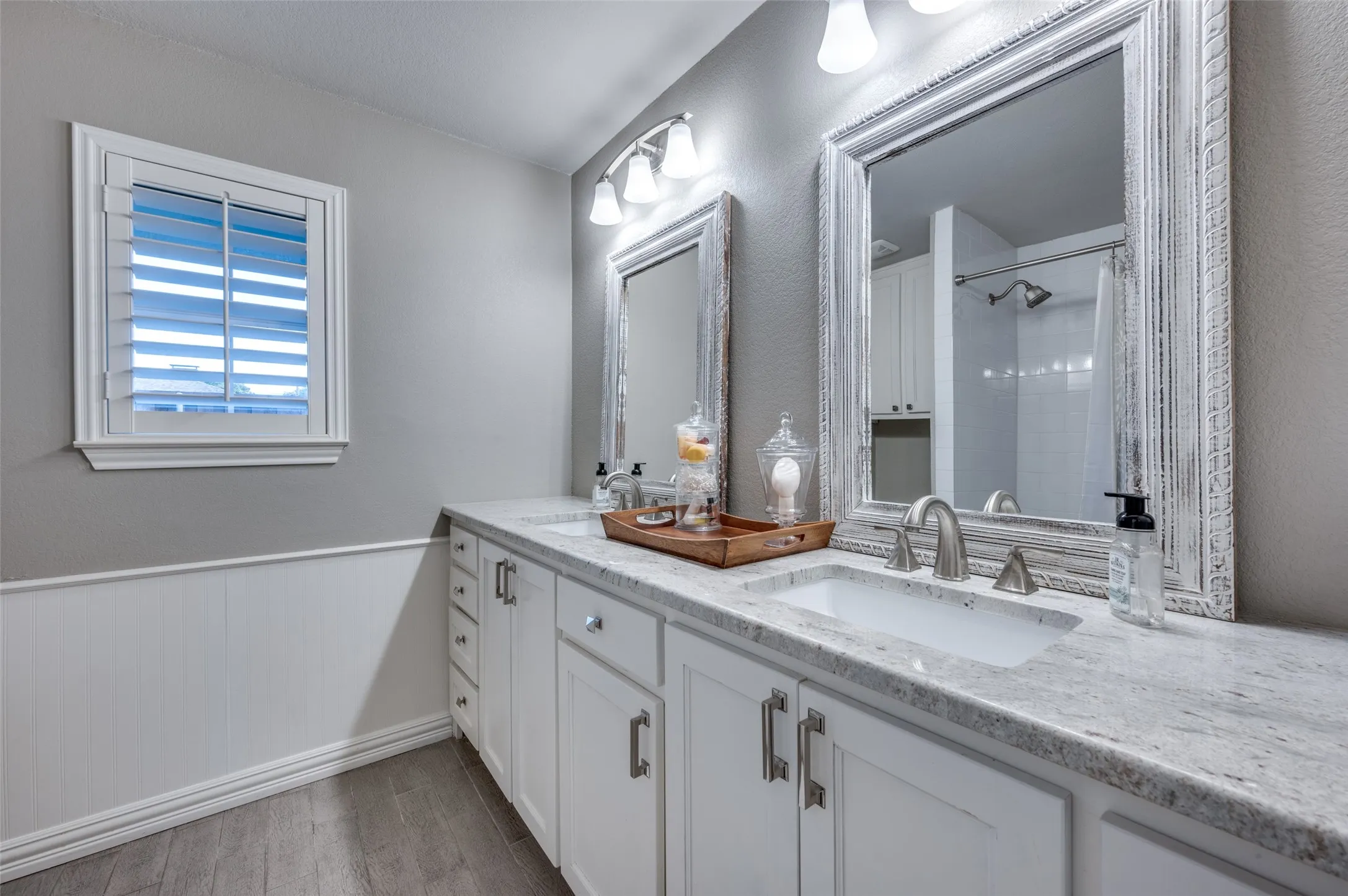 Bathroom featuring double vanity, wood finished floors, and a shower