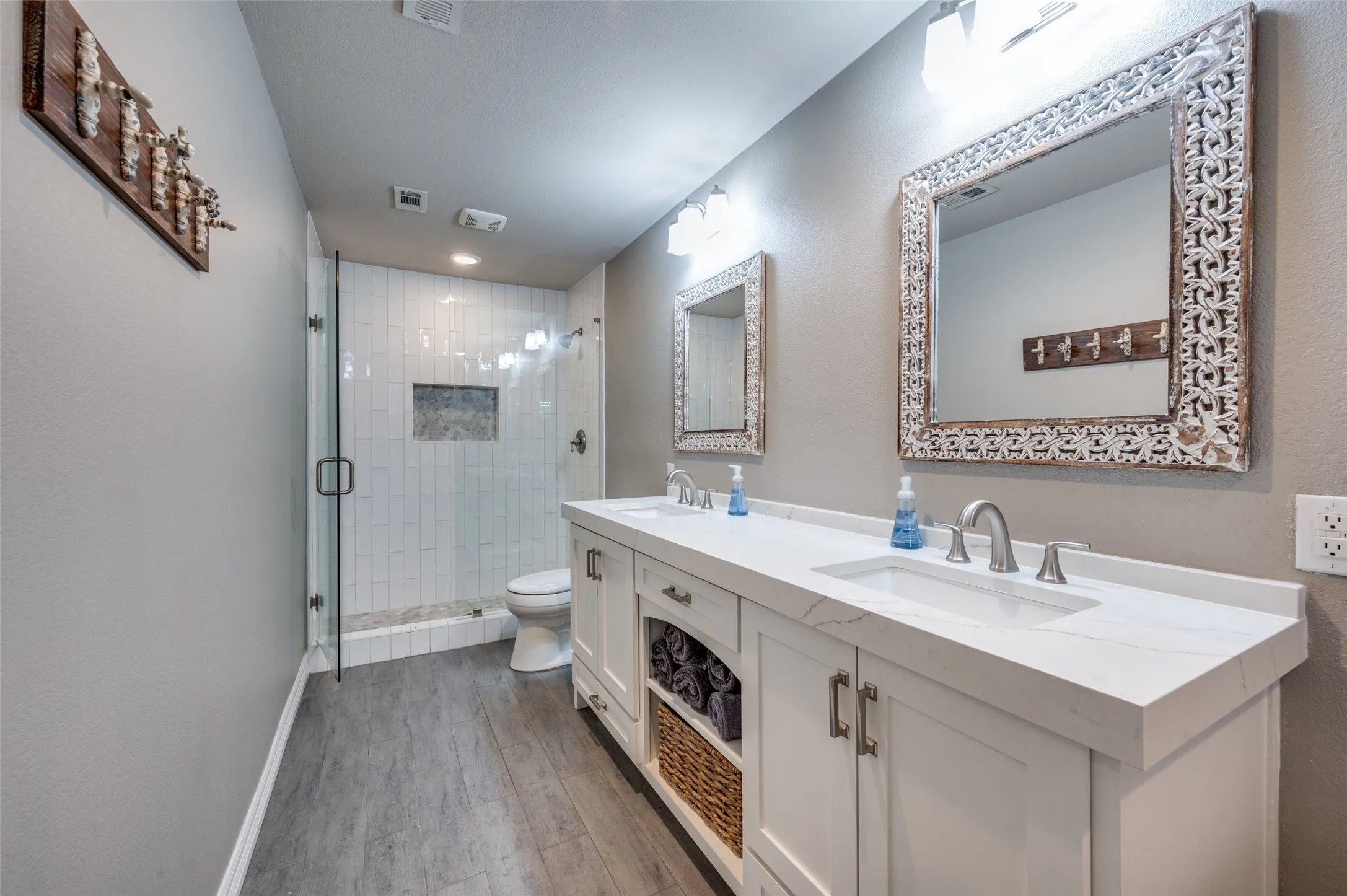 Bathroom with wood finished floors, double vanity, a stall shower, and recessed lighting