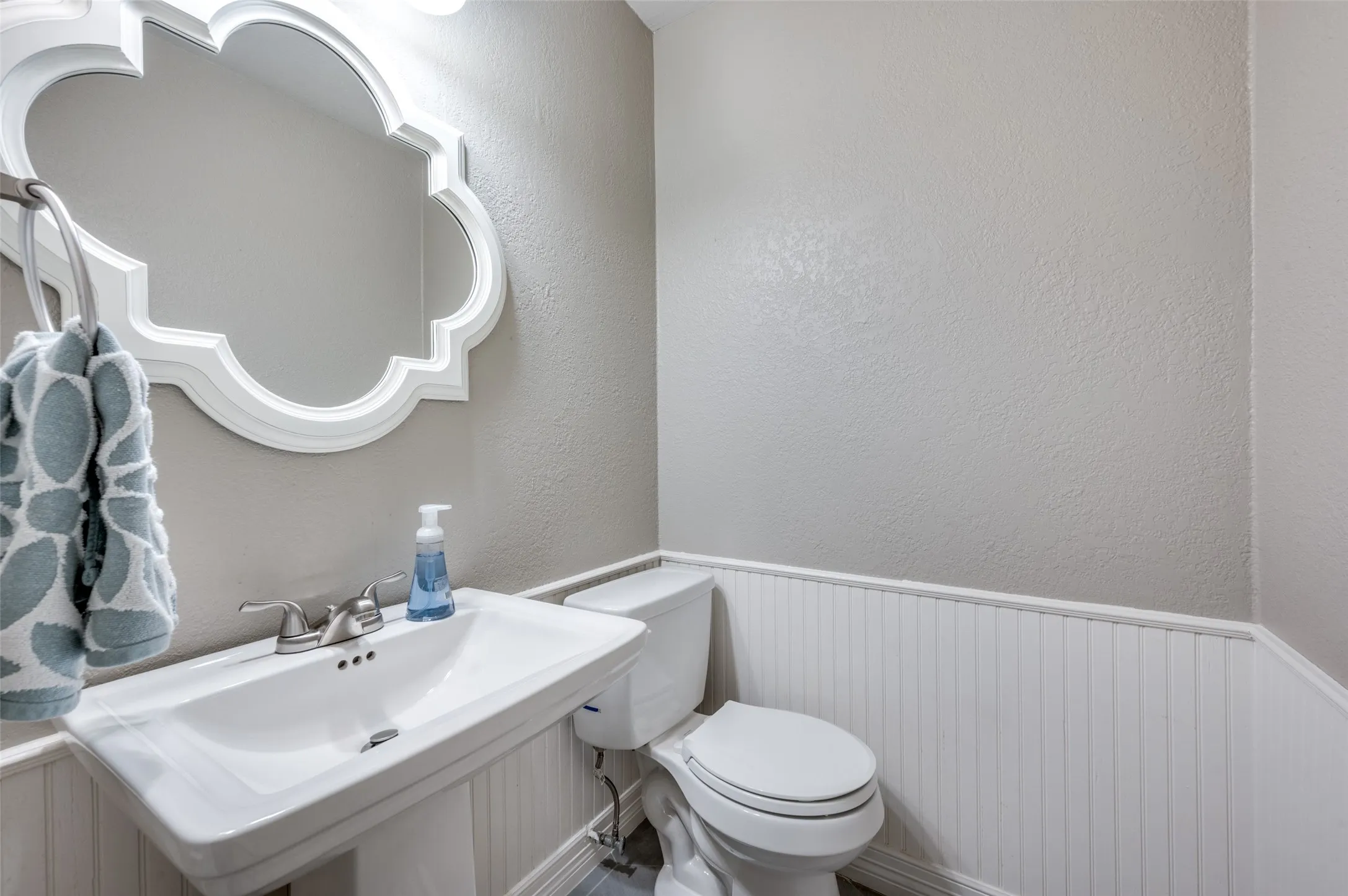 Half bath featuring a wainscoted wall and a textured wall