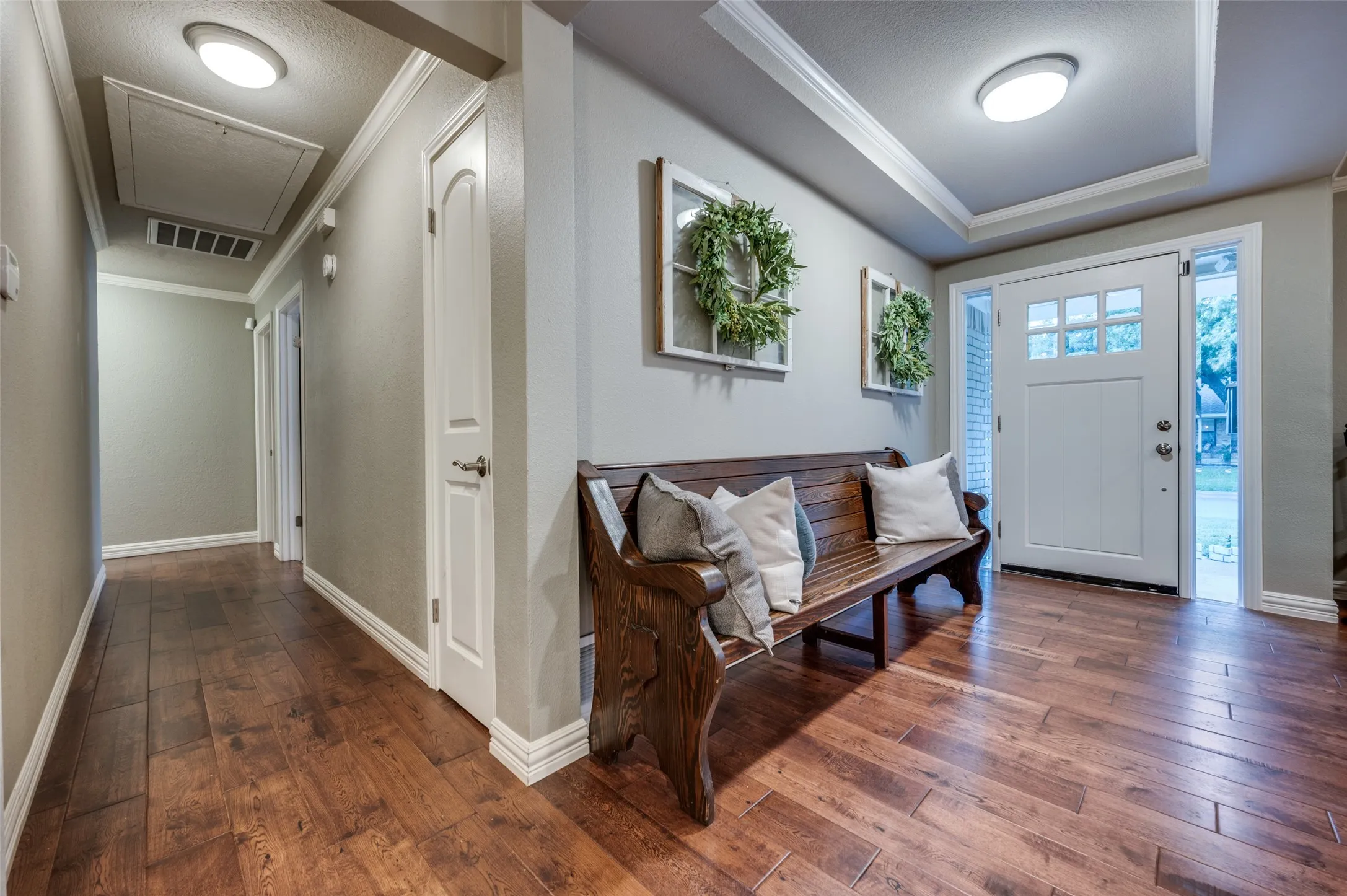Entryway with dark wood-style flooring, ornamental molding, and a raised ceiling