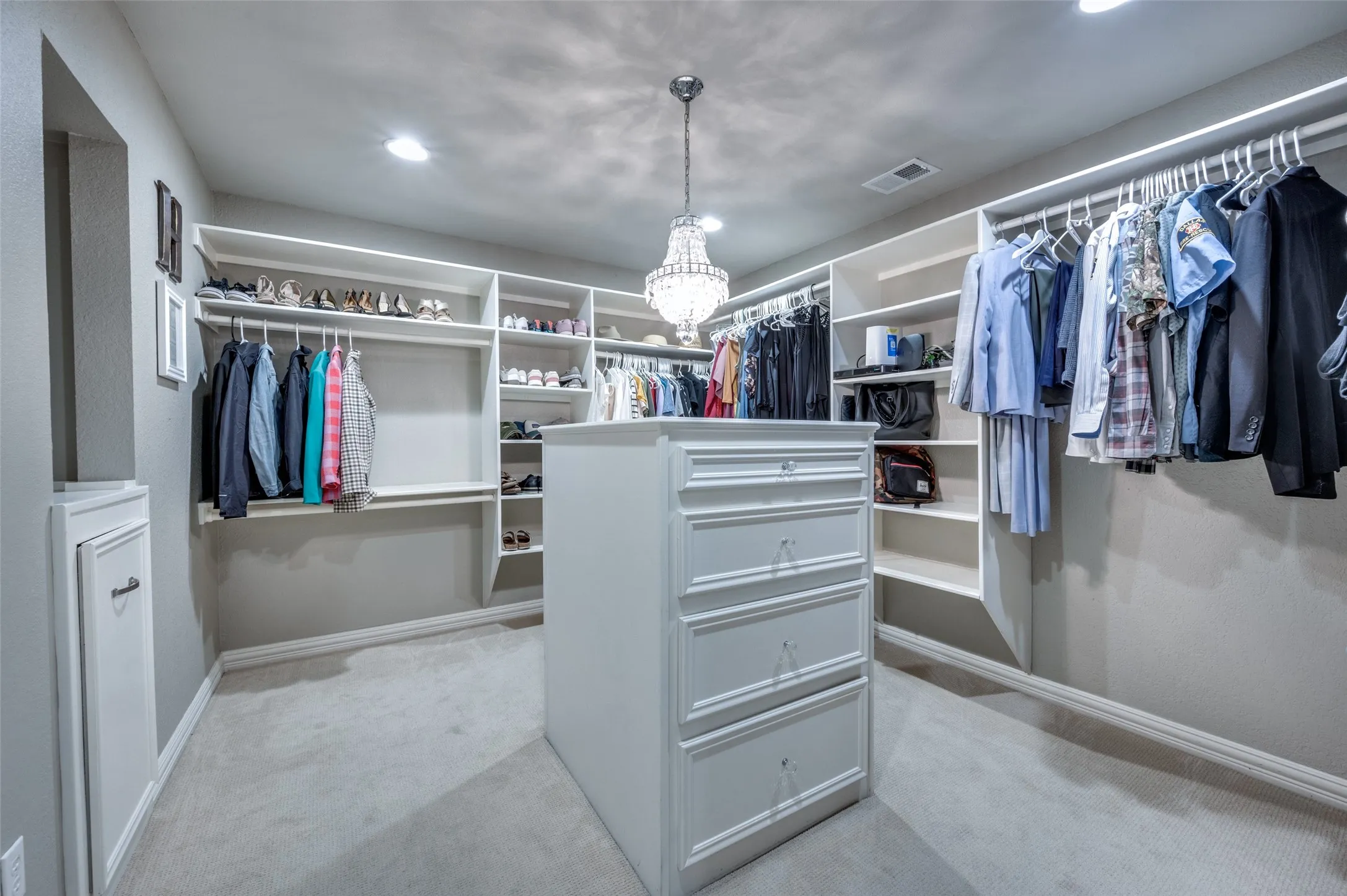 Walk in closet with a chandelier and light carpet