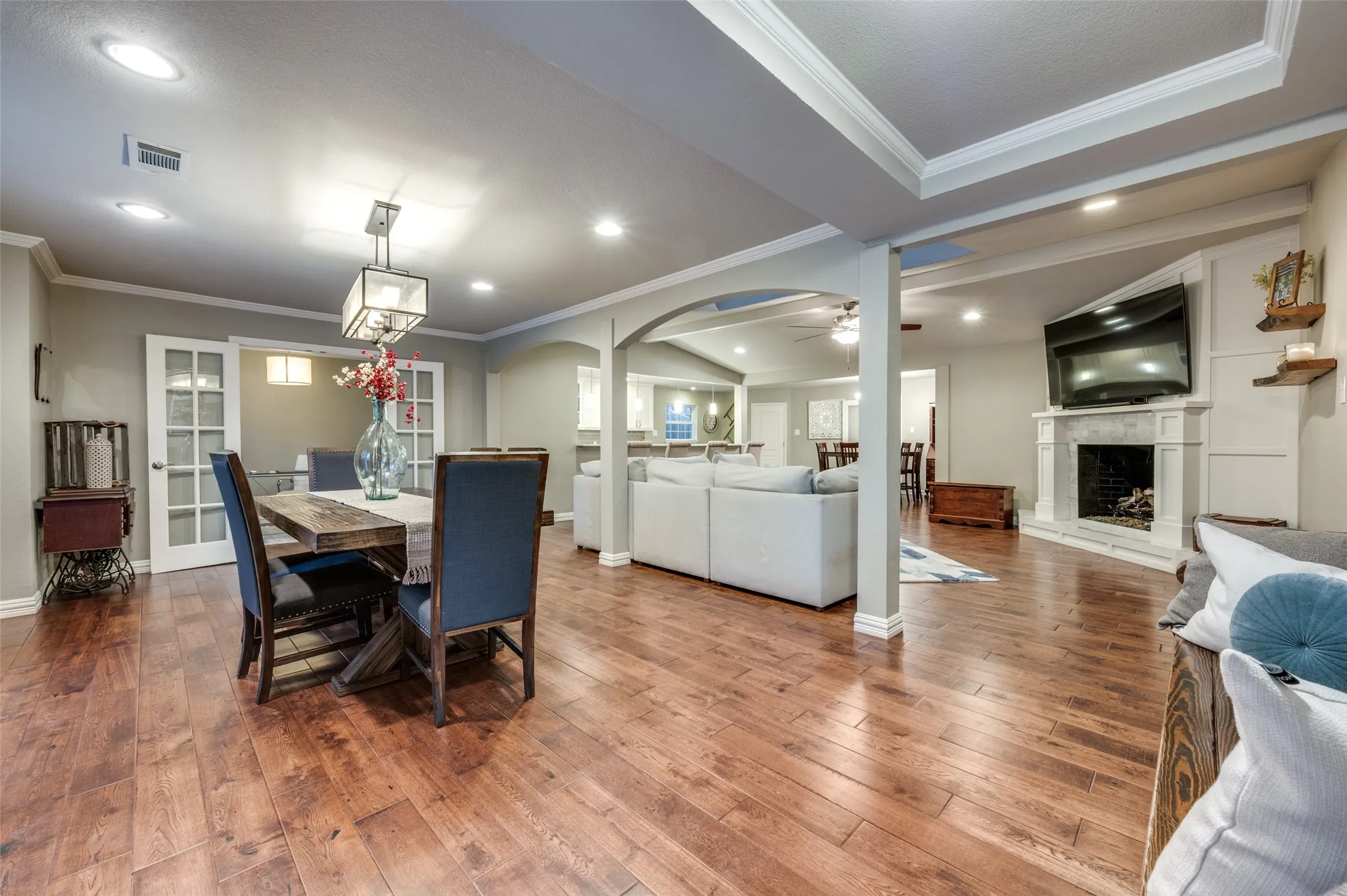 Dining area featuring arched walkways, wood-type flooring, a ceiling fan, recessed lighting, and a fireplace with raised hearth