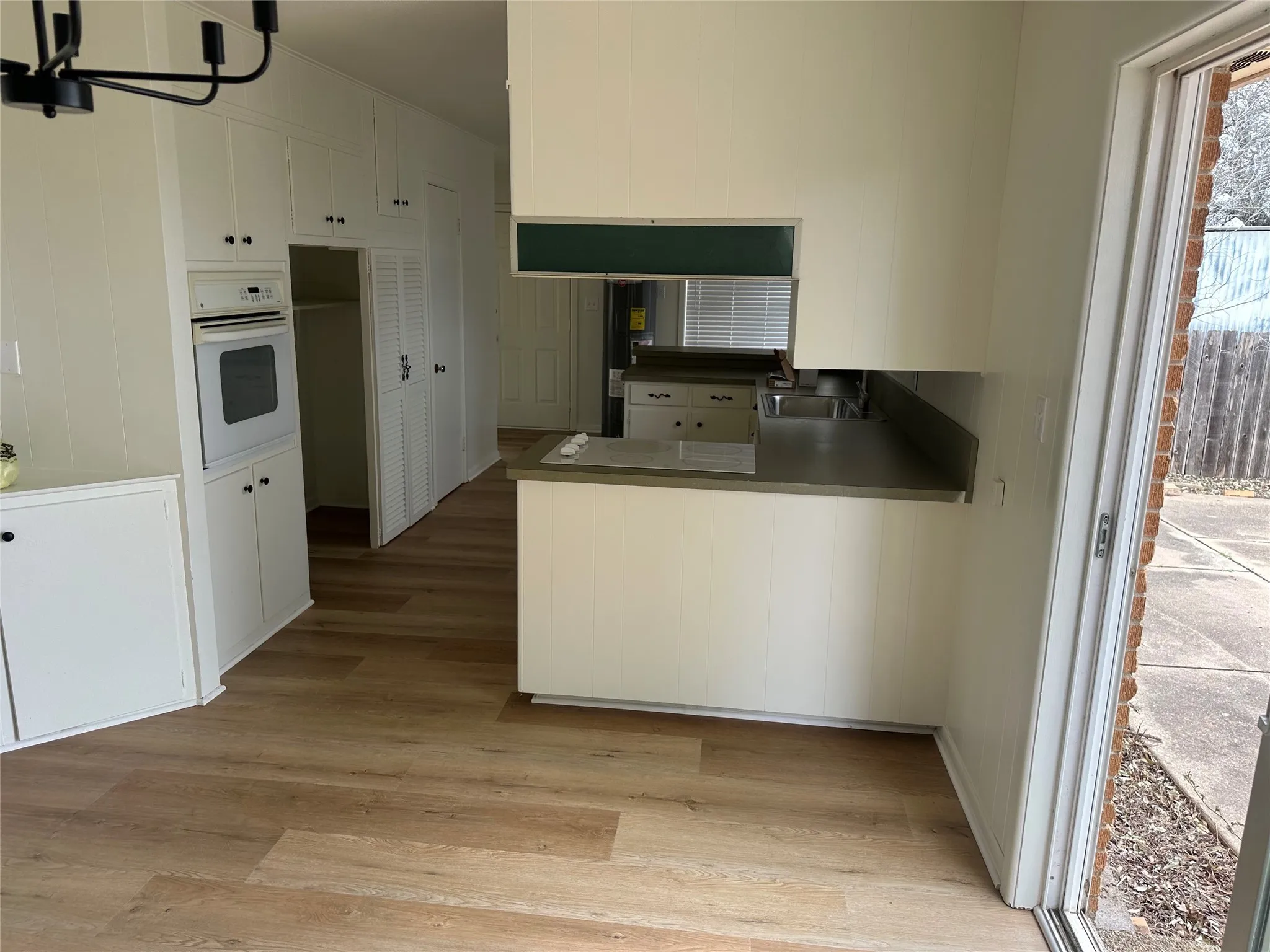Kitchen featuring oven, light wood-type flooring, white cabinets, and a peninsula