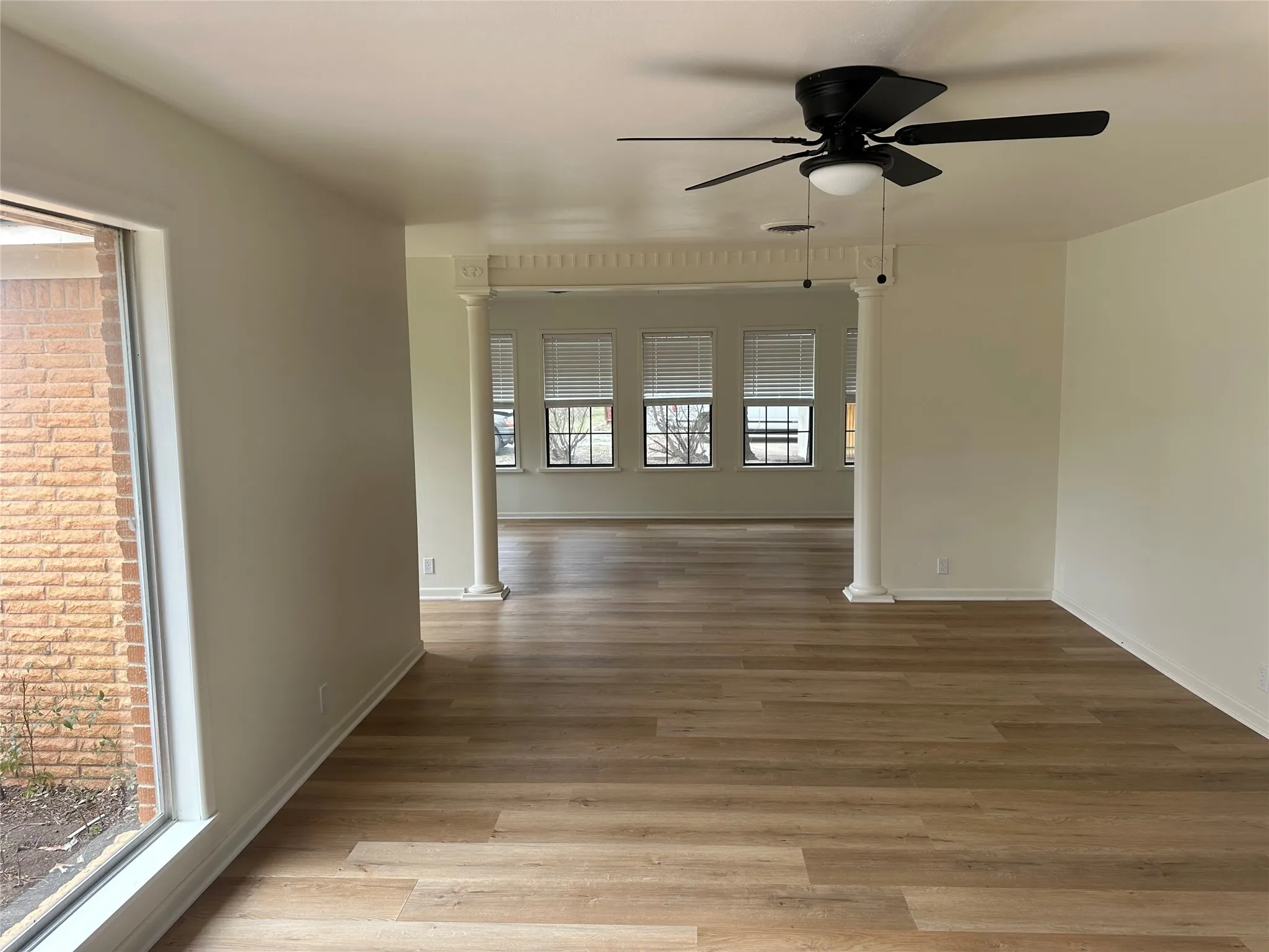 Living room with a ceiling fan, ornate columns, and wood finished floors