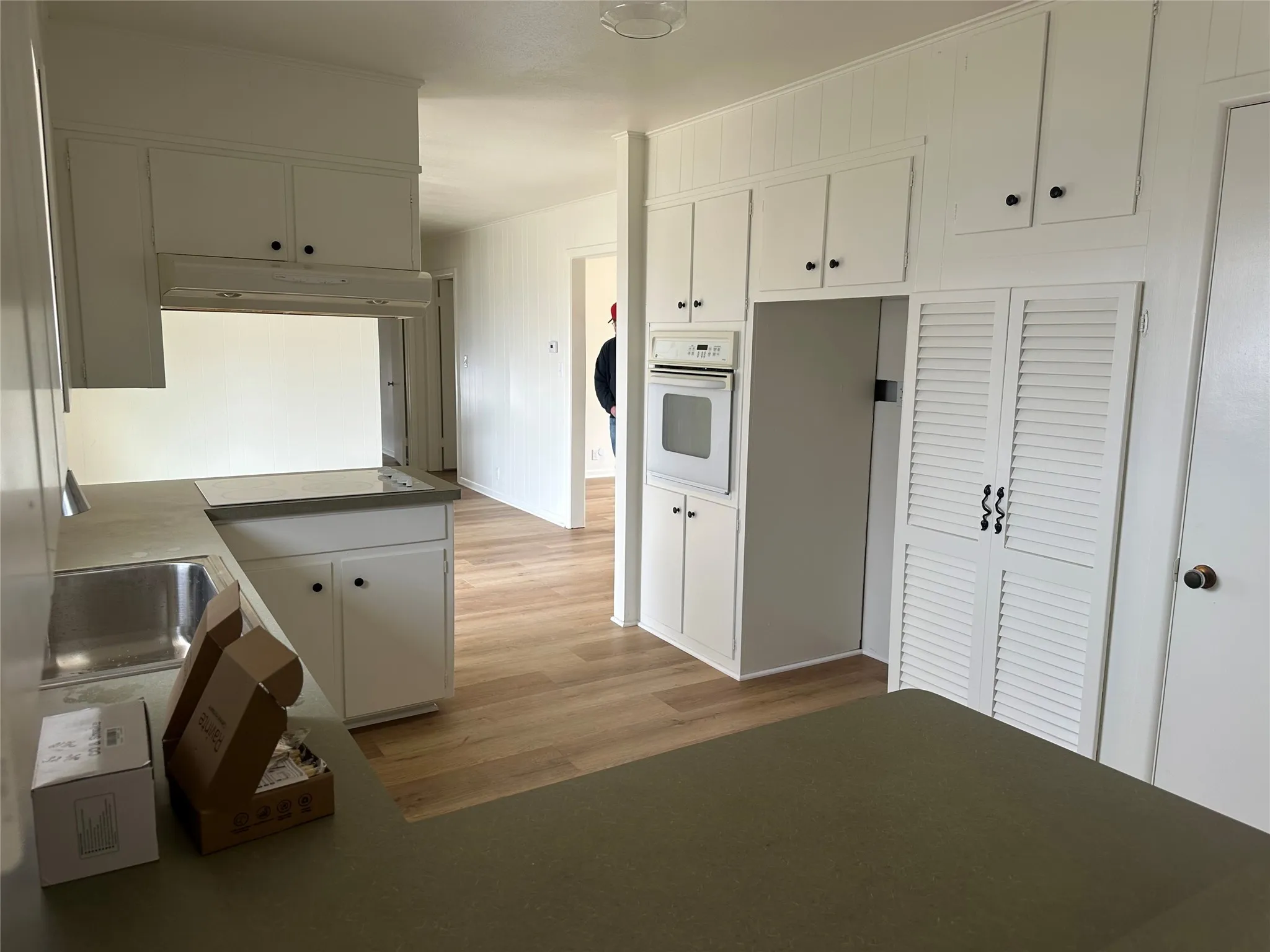 Kitchen featuring white appliances, under cabinet range hood, and white cabinetry