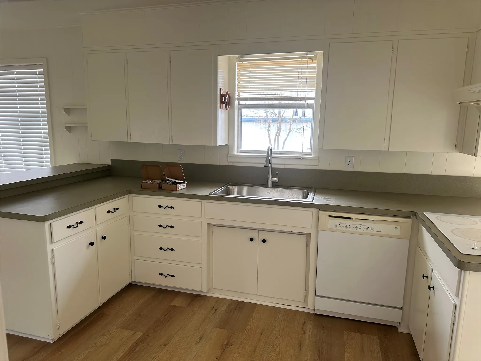 Kitchen with white appliances, a peninsula, and white cabinetry