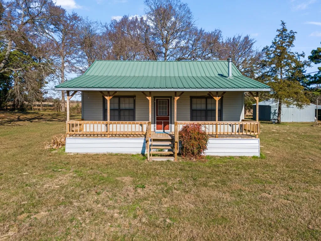View of front of house with covered porch, a front yard, and a metal roof