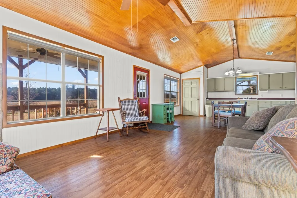 Living area featuring healthy amount of natural light, wood ceiling, wood finished floors, a chandelier, and vaulted ceiling