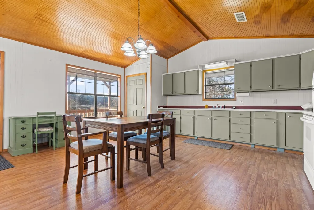 Dining area featuring light wood-style floors, lofted ceiling, a chandelier, and wood ceiling