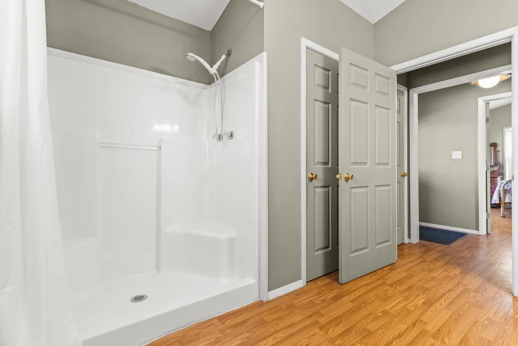 Full bath featuring a shower stall and light wood-style flooring