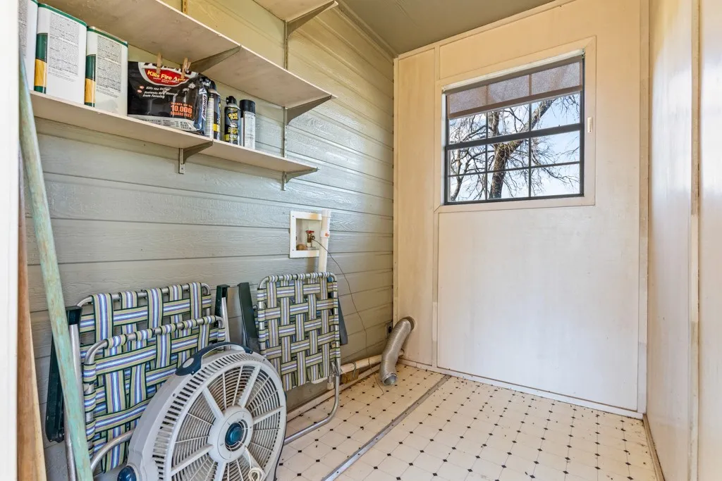 Washroom featuring wooden walls, tile patterned floors, and hookup for a washing machine