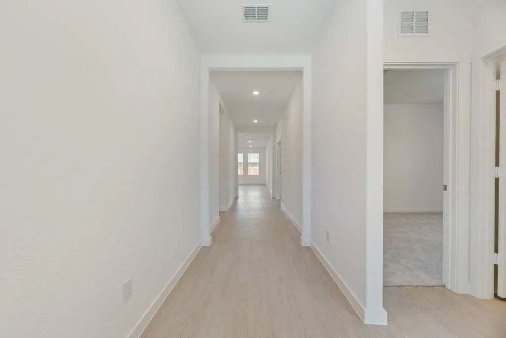 Hallway with light wood finished floors and recessed lighting