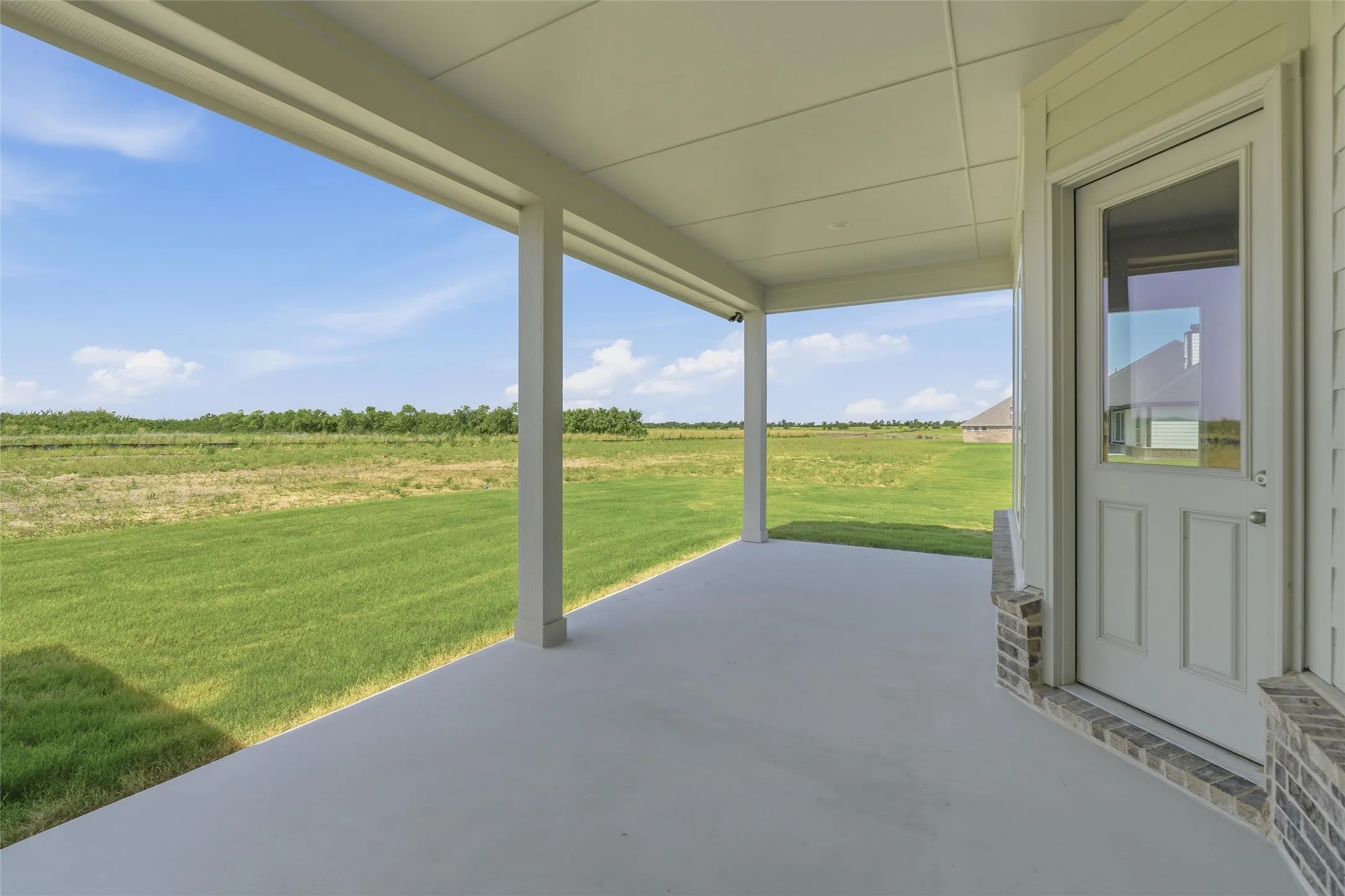 Covered patio featuring a concrete slab and white support columns