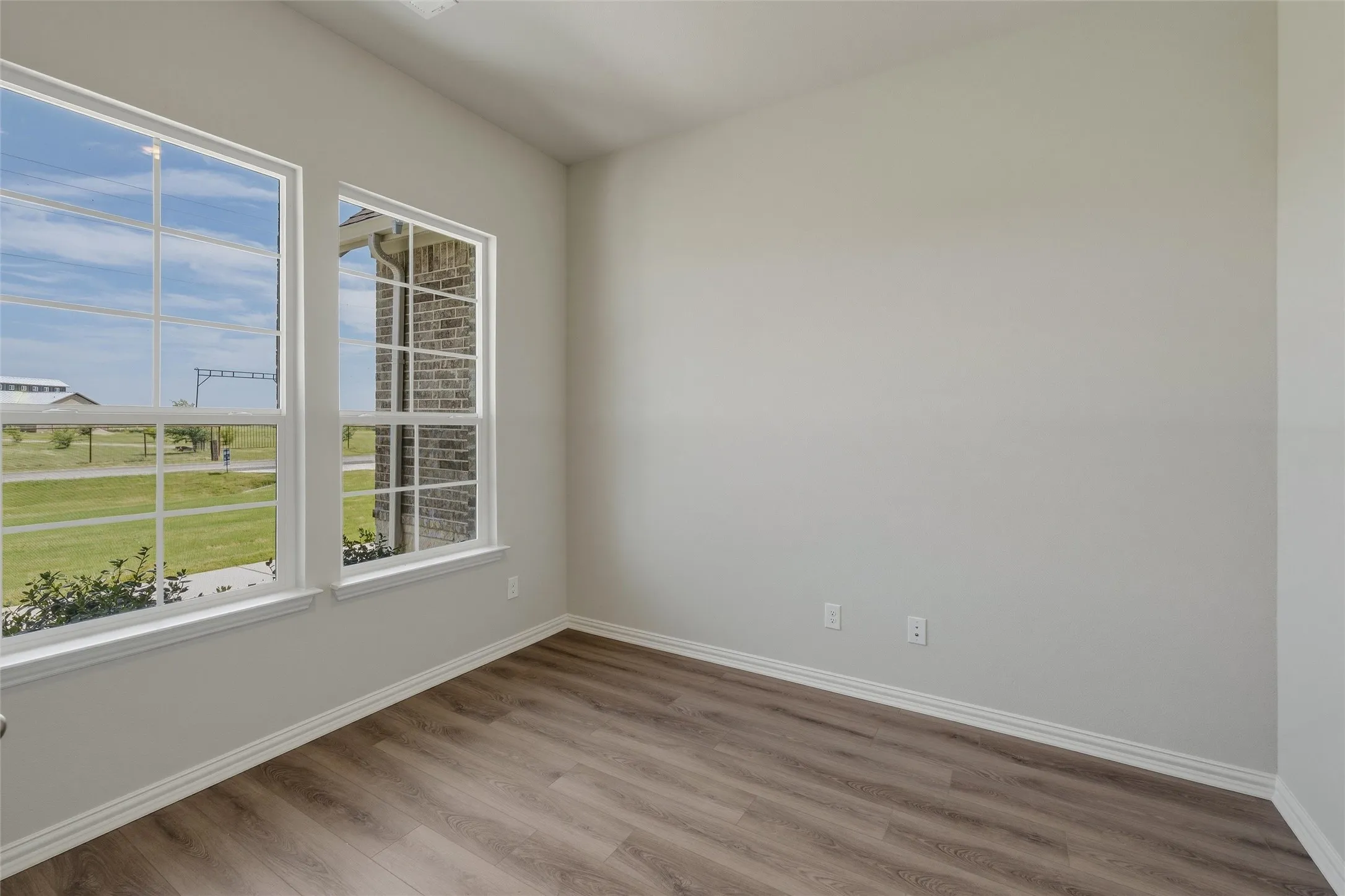 Room with wood-finish flooring, light gray walls, and white trim