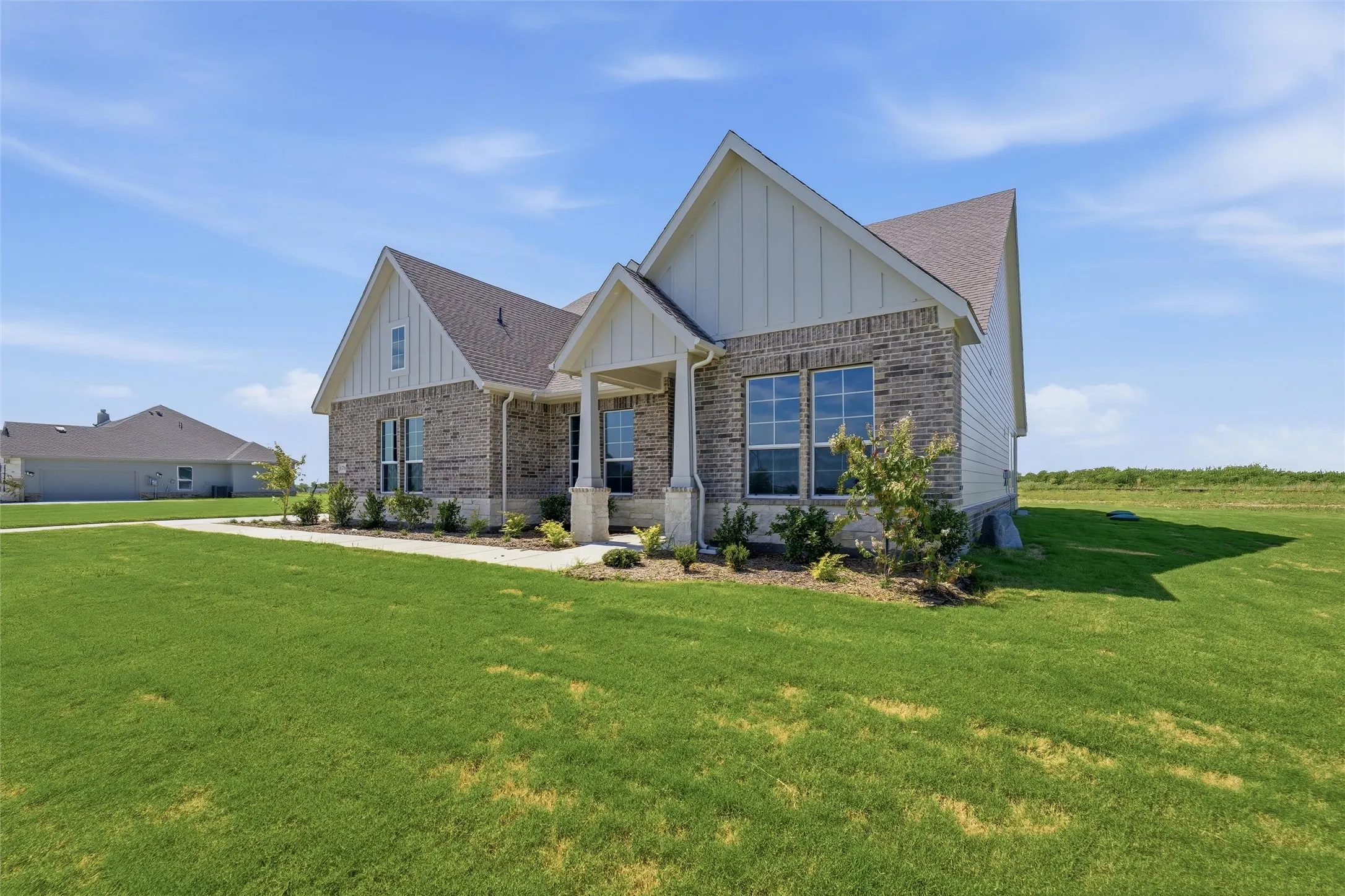 Single-story residence featuring a brick and horizontal siding exterior, a covered entry, gabled rooflines, and mature landscaping