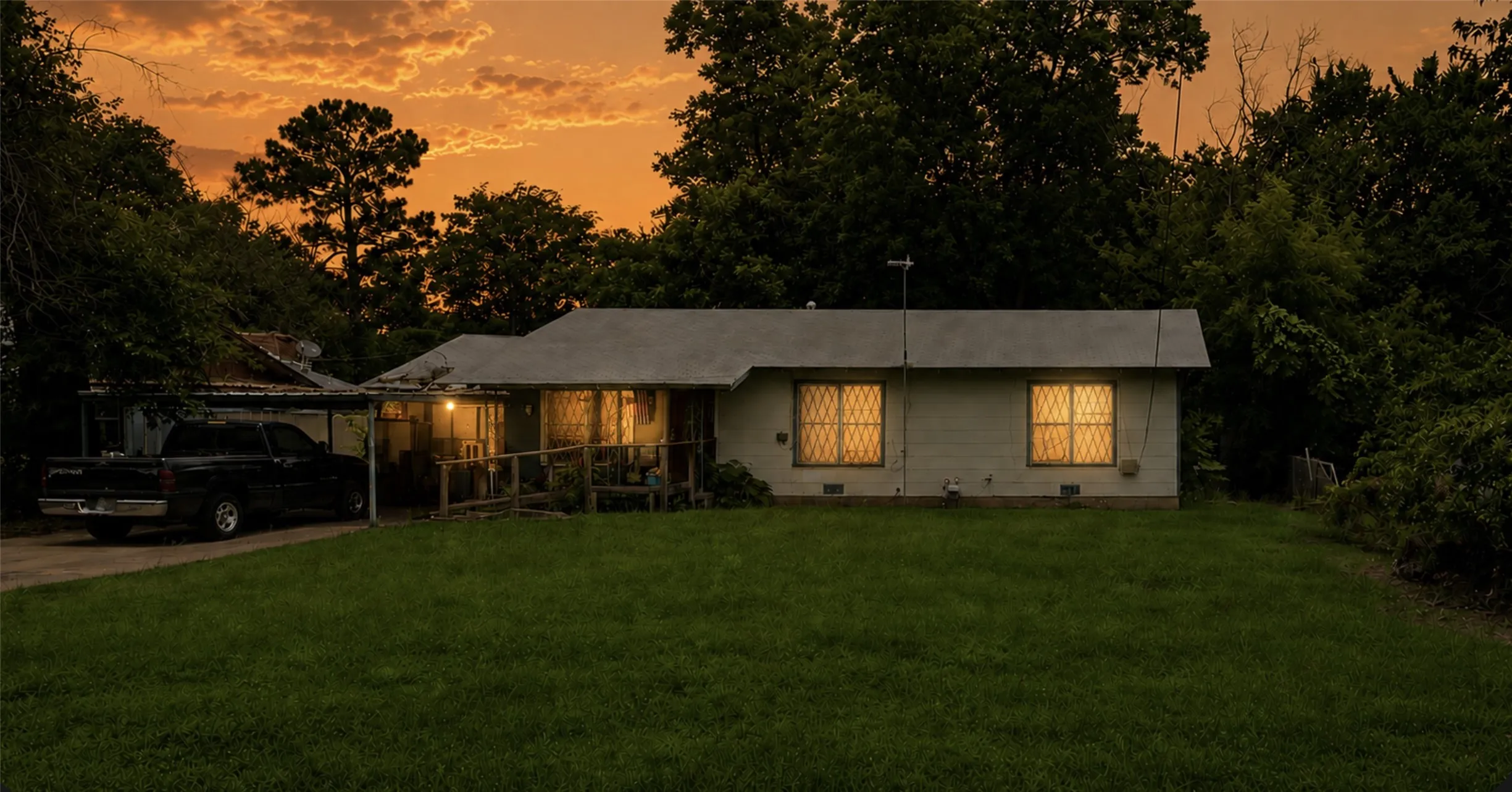 Virtual Sunset Photo 235 Parkins. 2 of 2 homes included in this listing. Single-story residence featuring a covered front porch with a ramp entry, a paved driveway, and a large front lawn