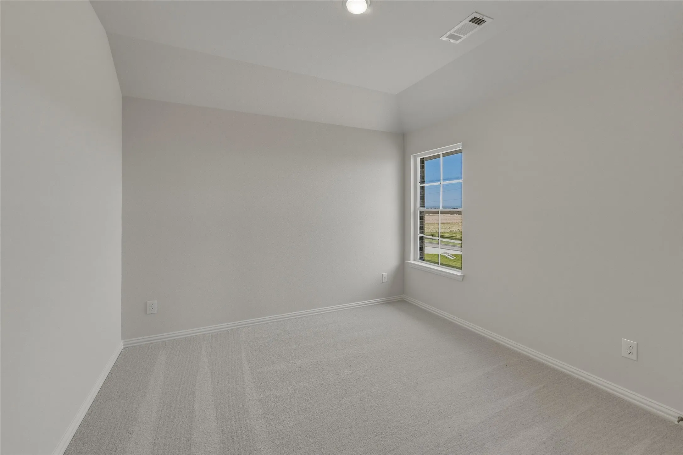 Light-filled room featuring a single-pane window, neutral-toned walls, gray carpeting, and white baseboards