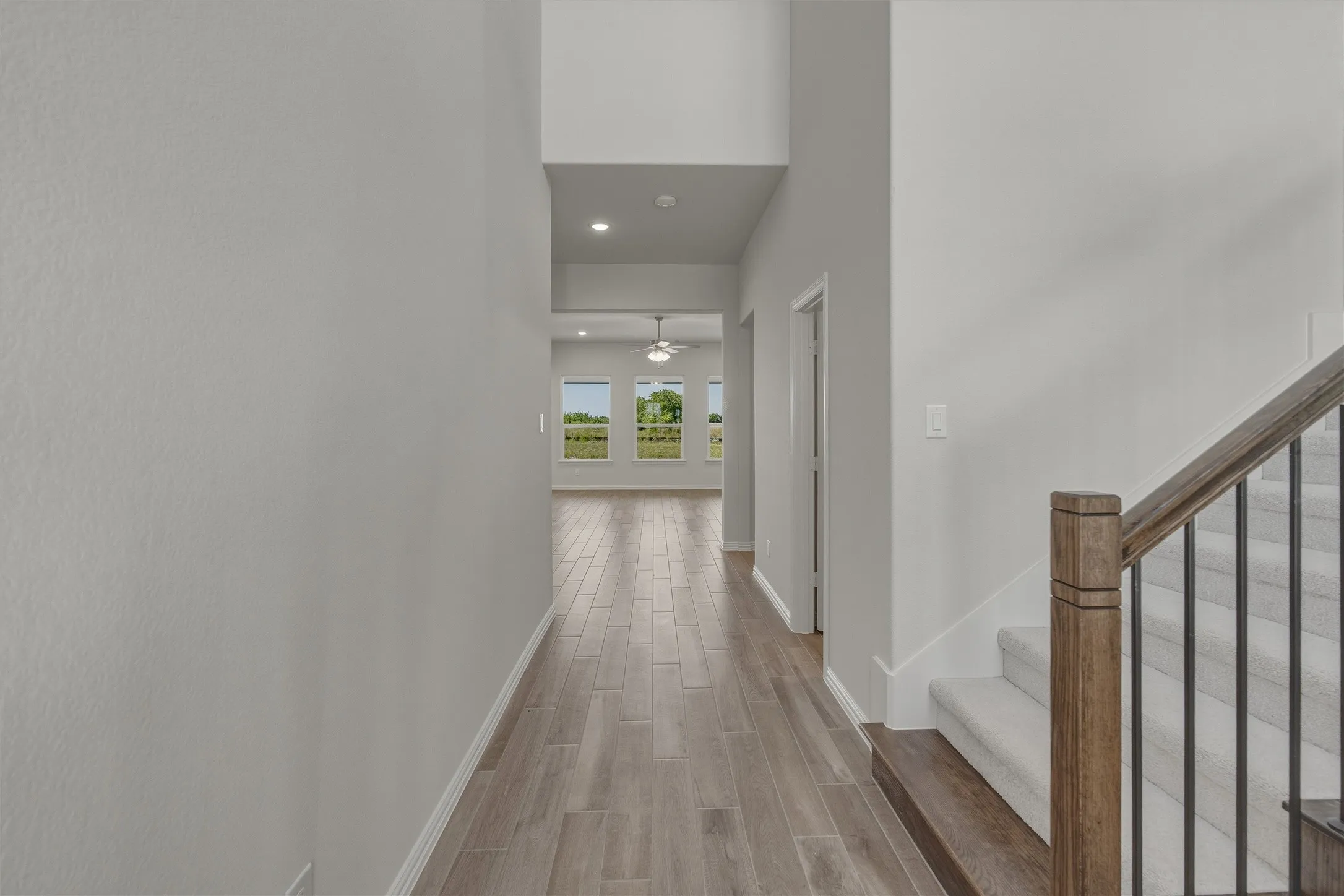 Hallway featuring wood-finish flooring extending into the background, light gray wall paint, and recessed lighting