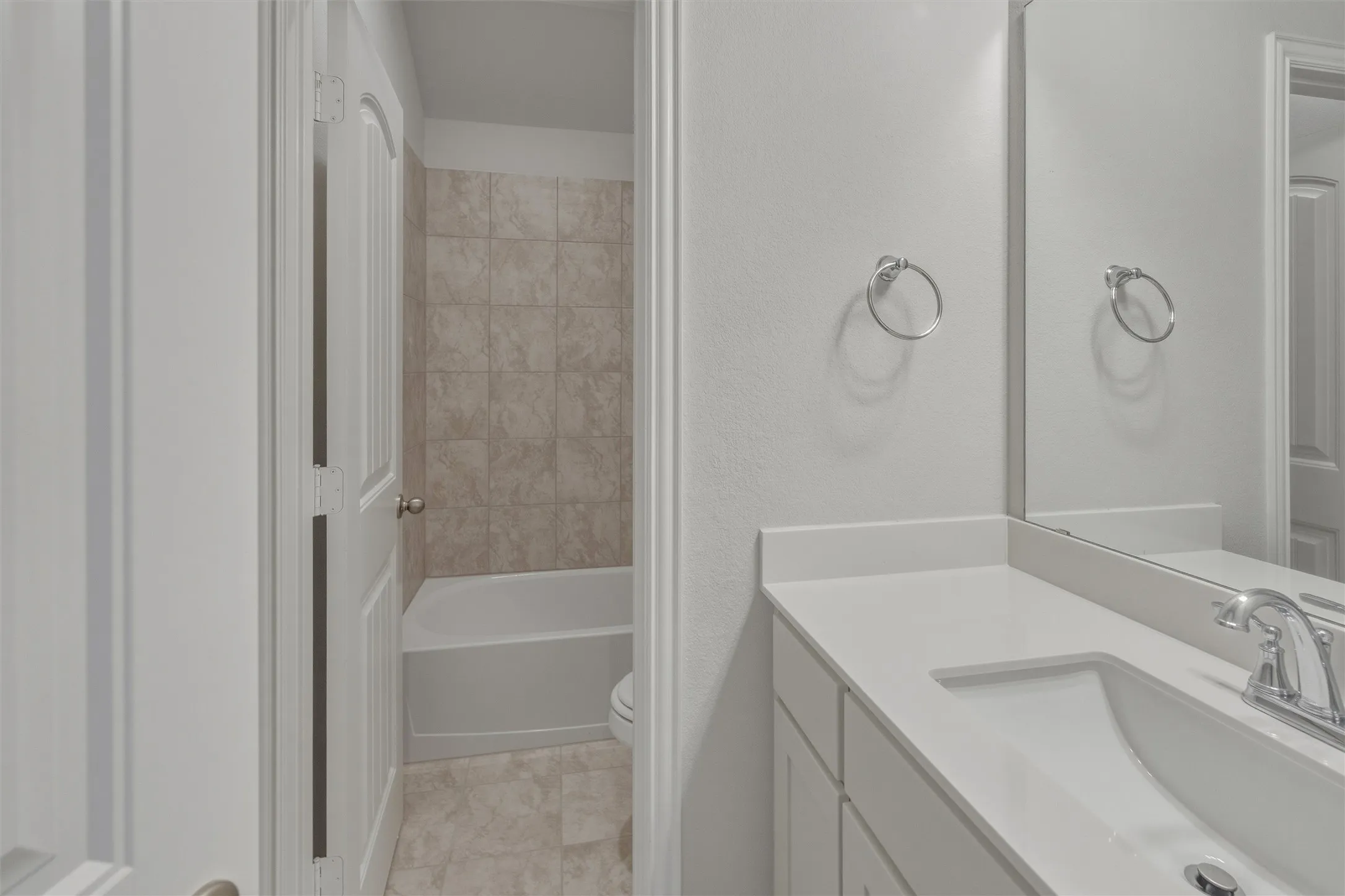 Bathroom vanity featuring a white countertop with an integrated sink and chrome faucet
