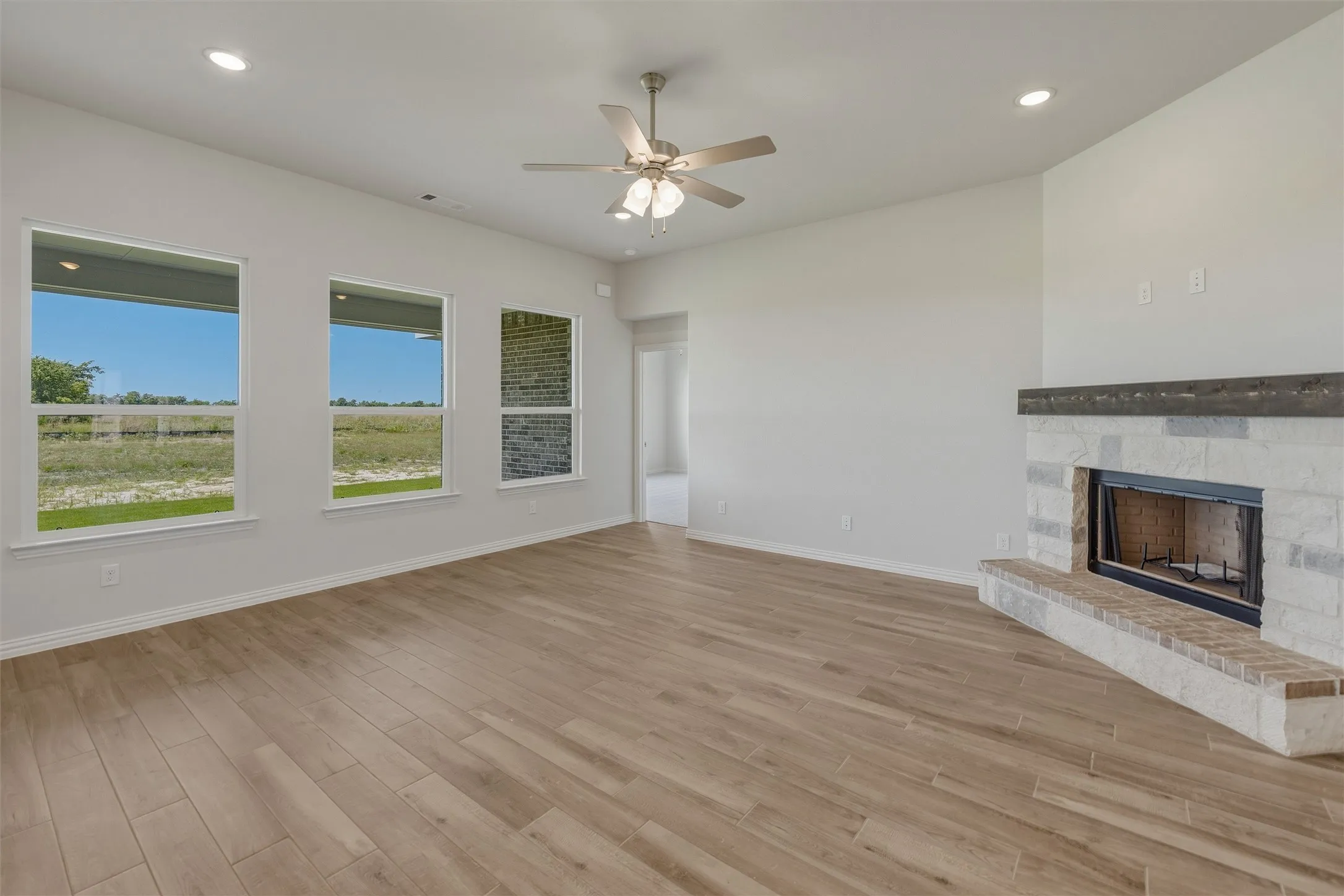 Spacious room with wood-finish flooring, a ceiling fan with integrated lighting, and recessed ceiling lights