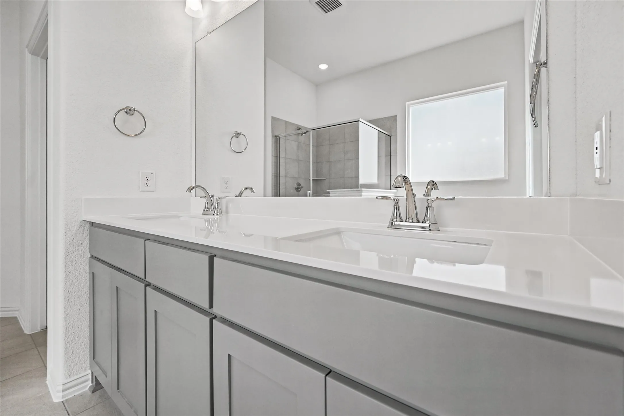 Double vanity with gray cabinetry, white countertops, and chrome fixtures