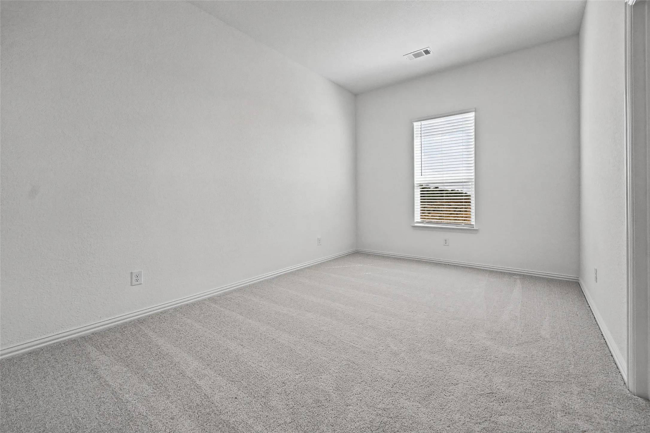Carpeted flooring, window with blinds, white painted walls, and an angled ceiling