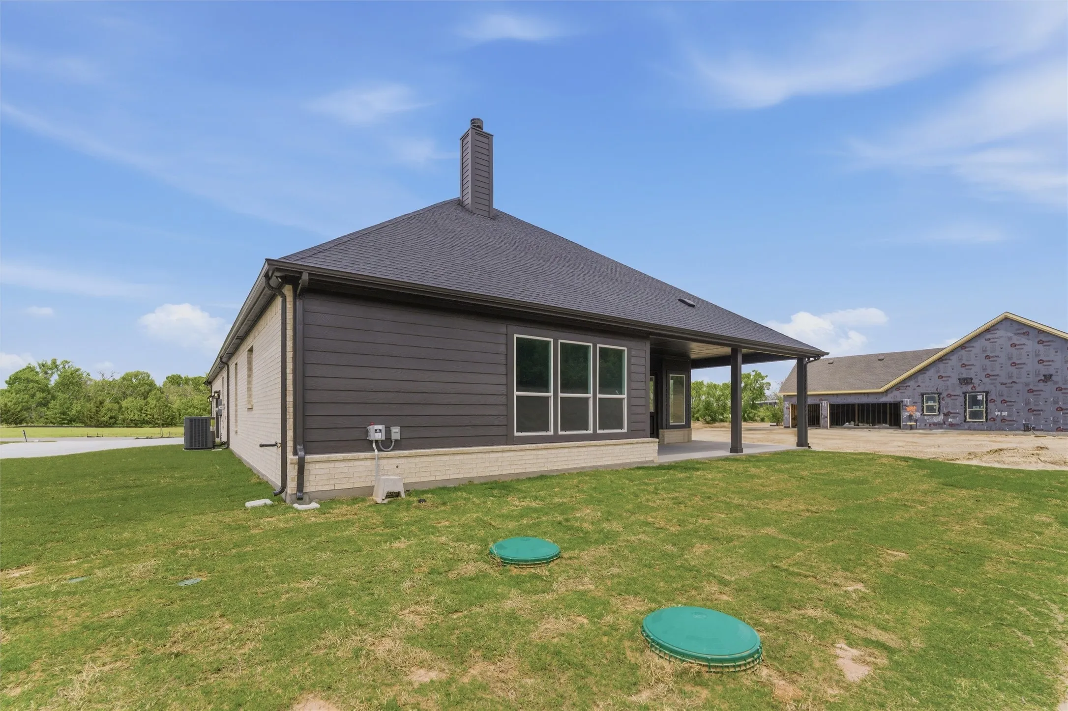 Back of house featuring a yard, a patio, a chimney, and roof with shingles
