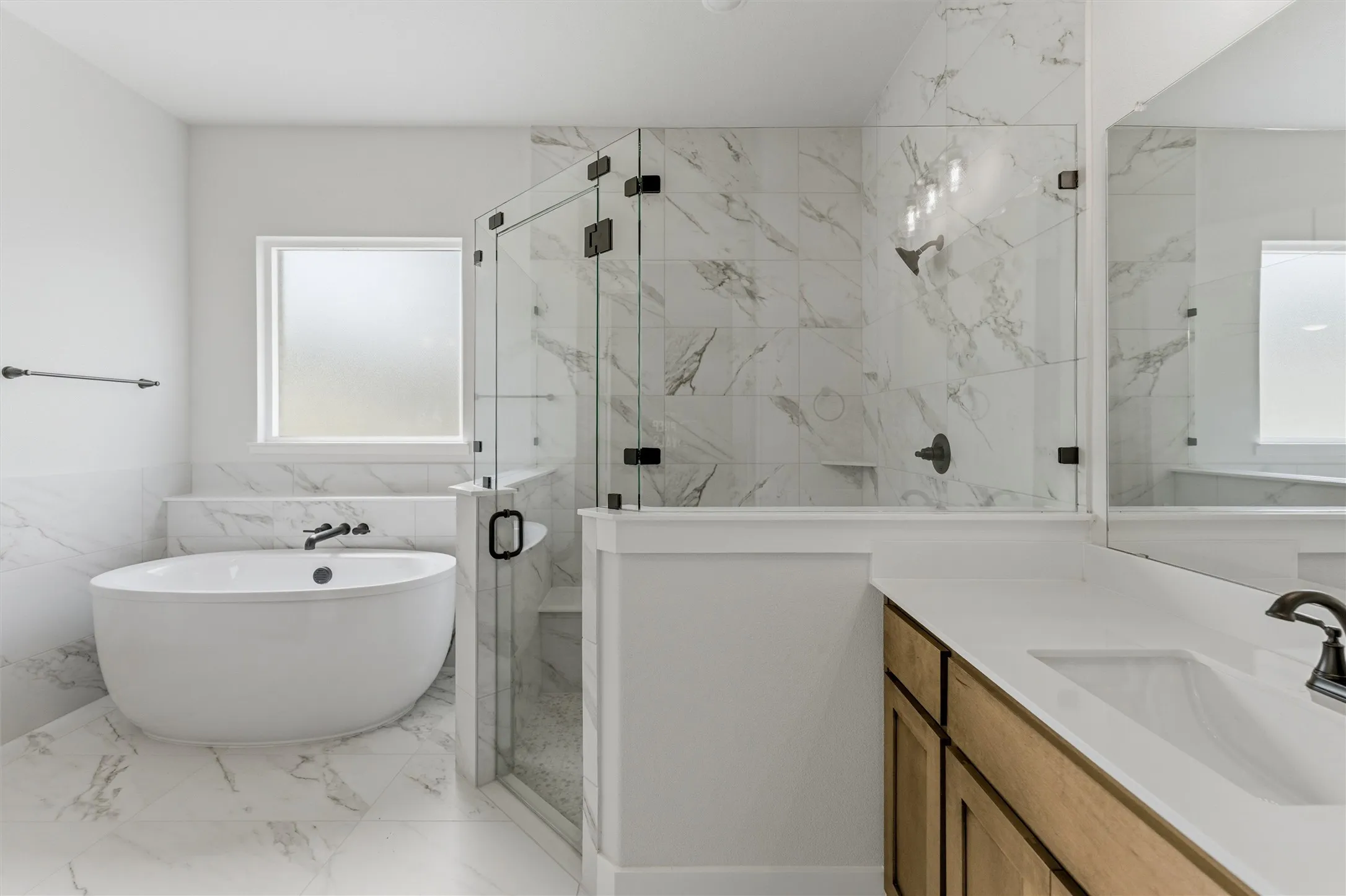 Bathroom with a marble finish shower, vanity, a freestanding bath, tile walls, and light marble finish floors