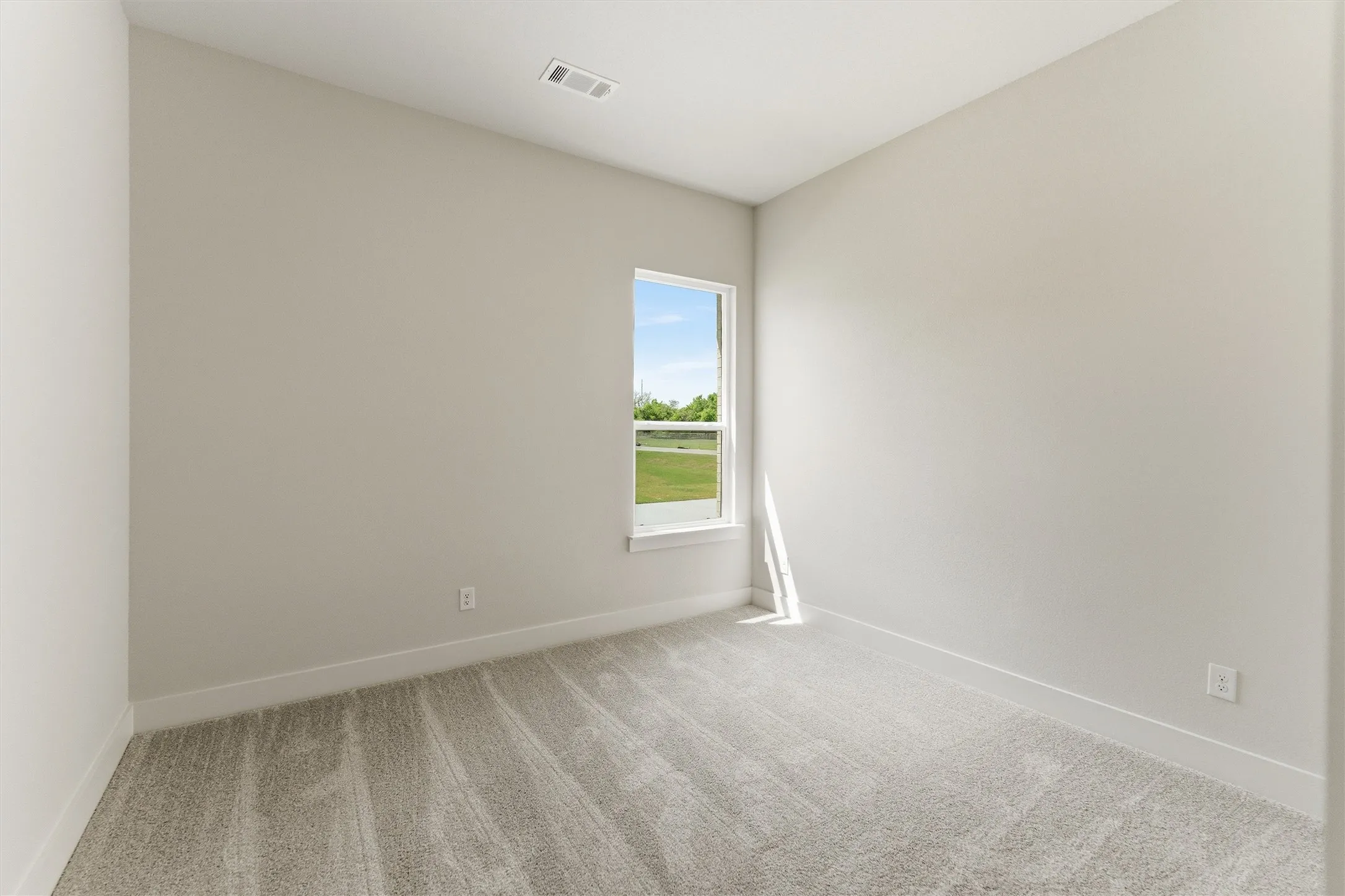 Unfurnished room featuring light carpet and baseboards