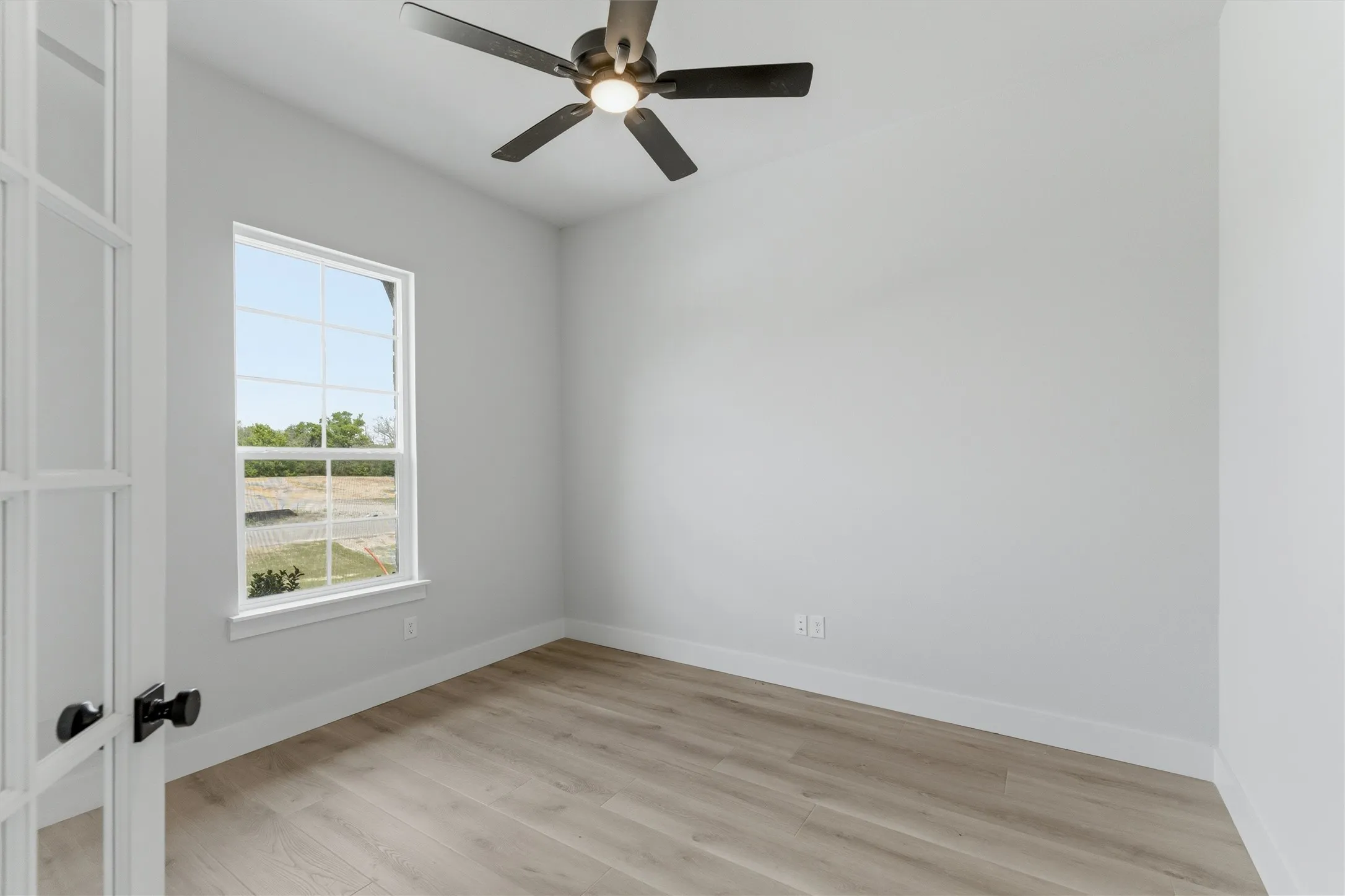 Unfurnished room with light wood-style floors, ceiling fan, and french doors