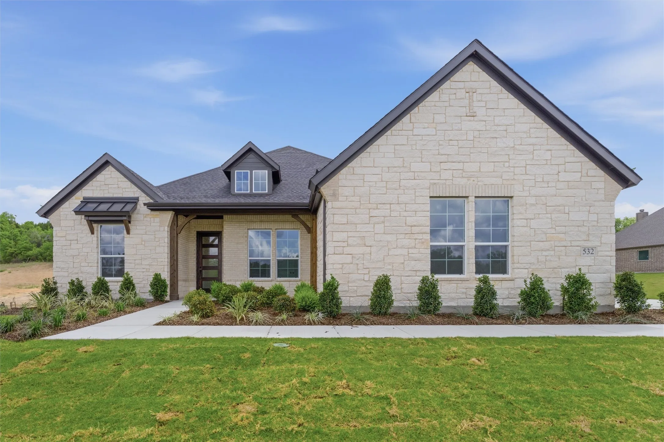 View of front facade featuring a front yard and stone siding