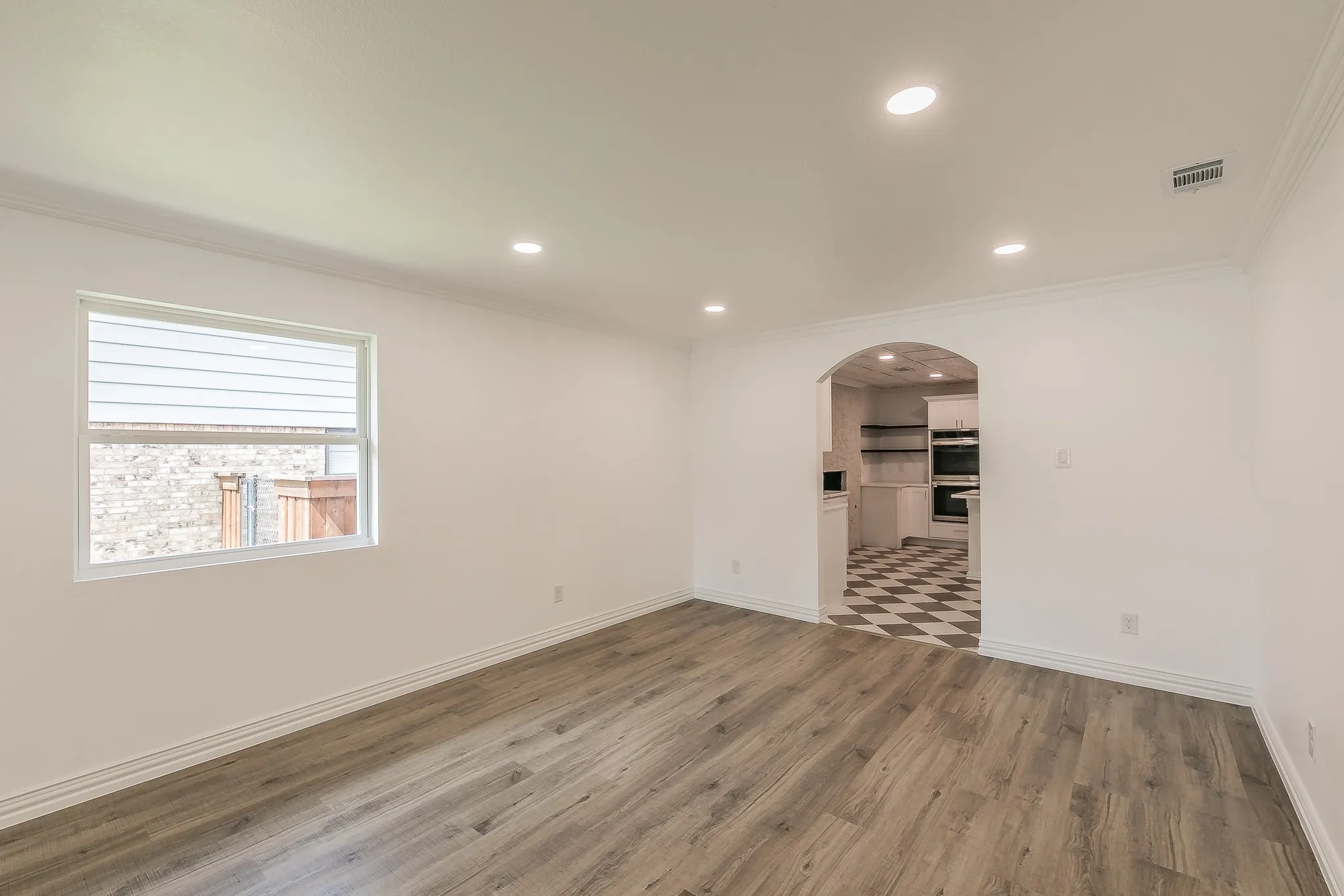 Spare room with arched walkways, wood finished floors, ornamental molding, and recessed lighting